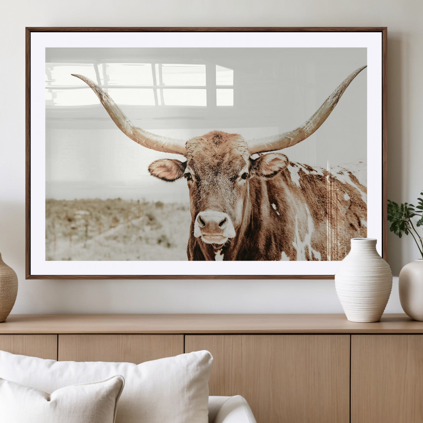 A Texas longhorn bull with wide horns, standing in a dry field under soft light, ideal for rustic farmhouse or western-themed interiors.