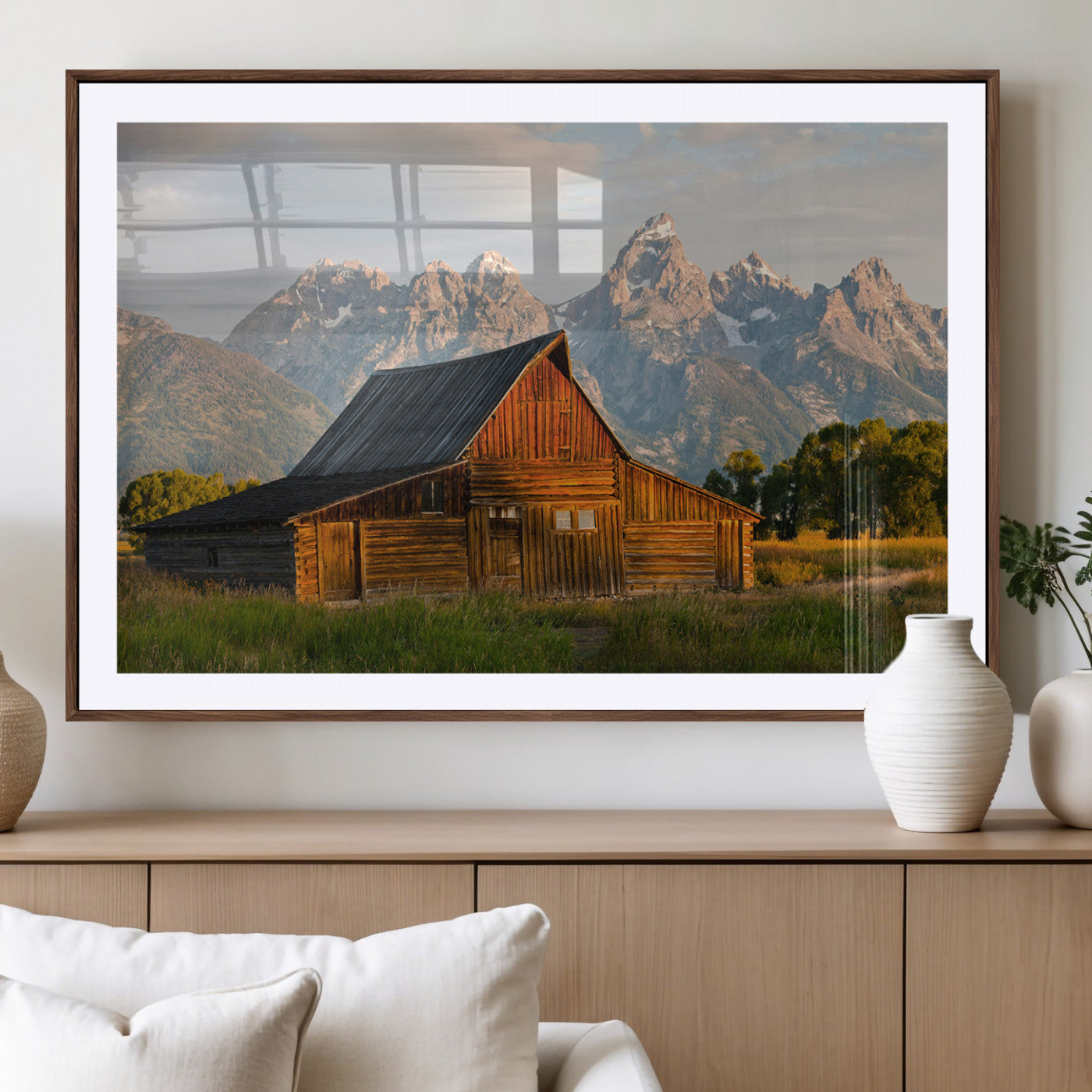 Rustic wooden barn set against towering mountain peaks under warm golden light, creating a peaceful Western countryside scene.