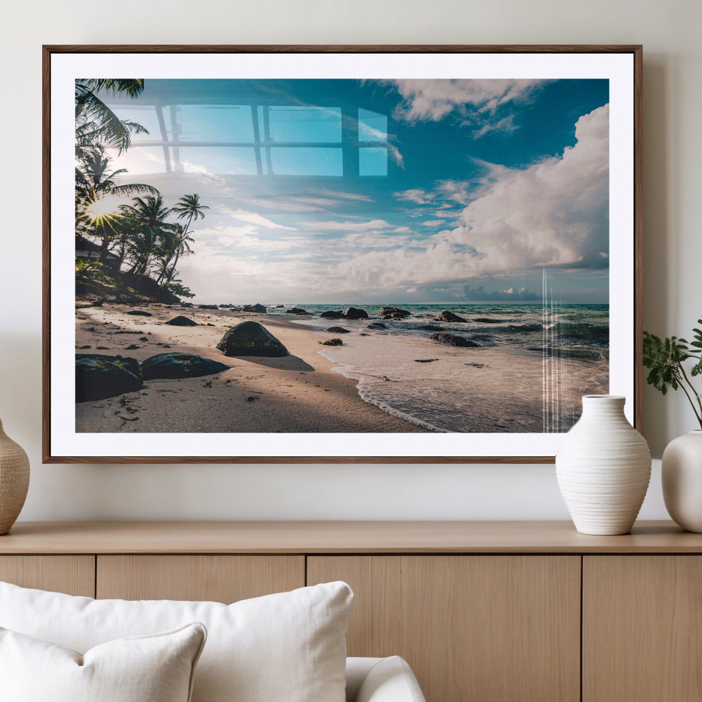 Scenic tropical beach with palm trees, ocean waves, and rocky shoreline under a bright blue sky, creating a serene coastal vibe.