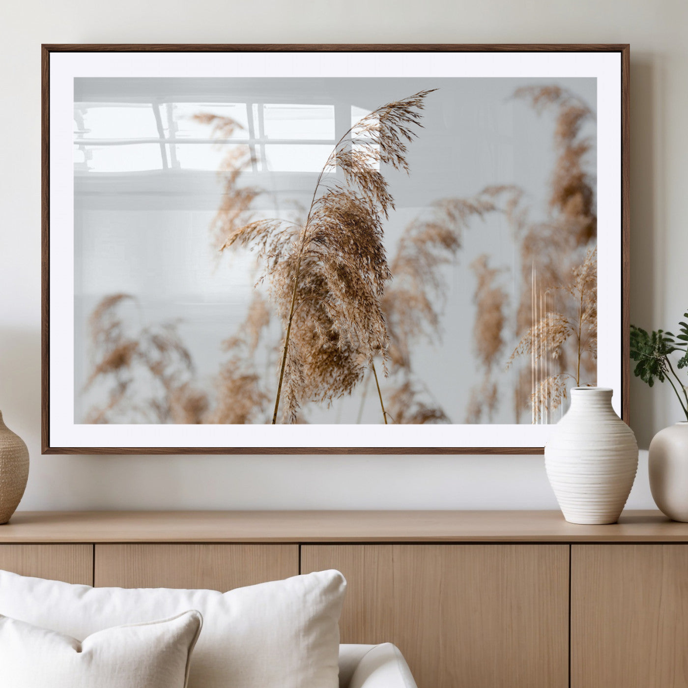 Close-up of pampas grass swaying in the wind against a soft white sky, creating a neutral and minimalist botanical aesthetic.