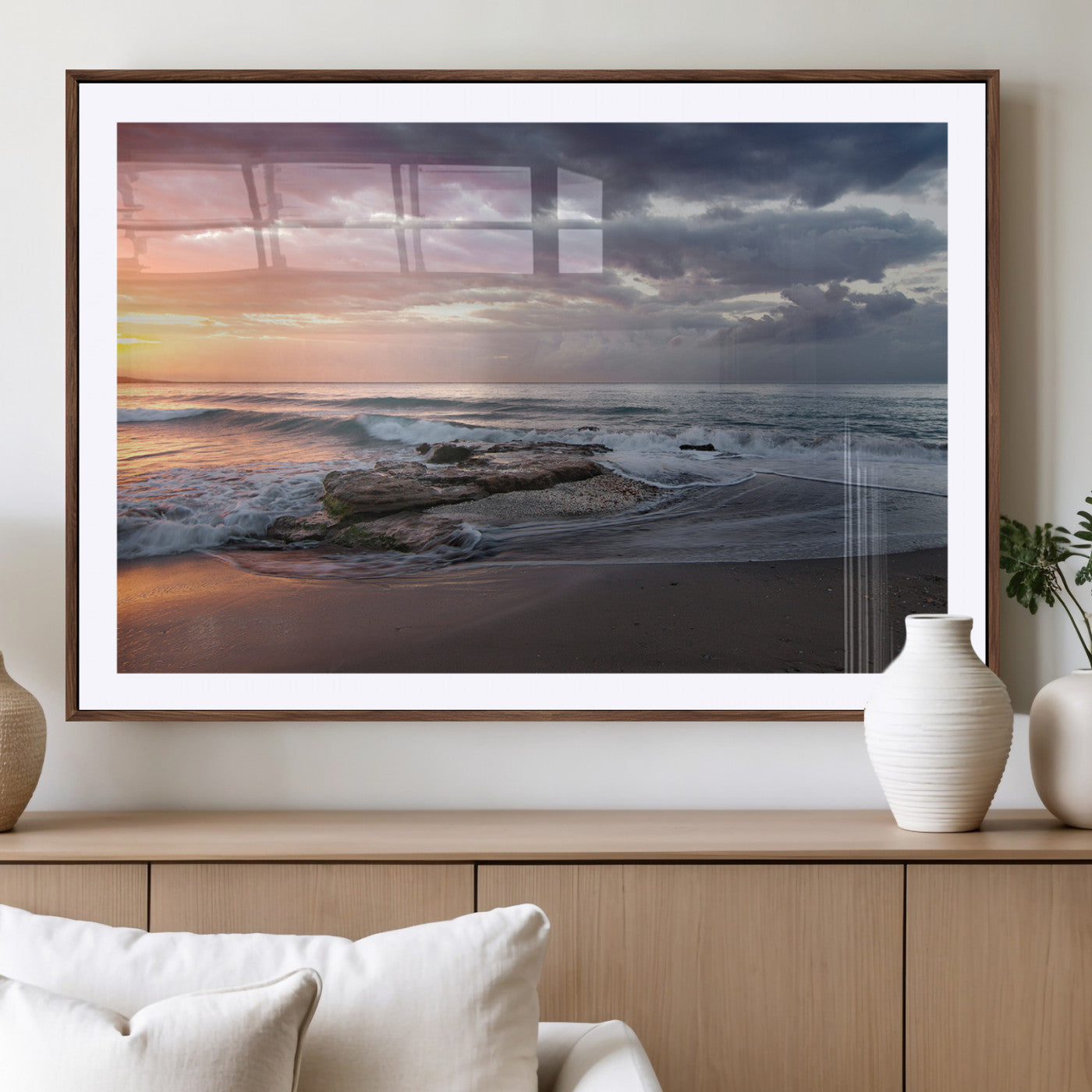 Dramatic sunset over a rocky shoreline with ocean waves gently reaching the sandy beach, creating a serene and coastal atmosphere.