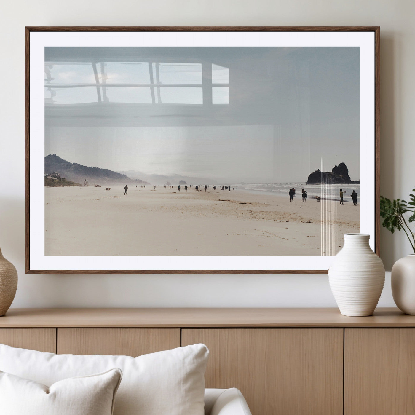 A serene beach with soft sand, misty mountains, and scattered people walking along the shoreline, creating a peaceful coastal landscape.