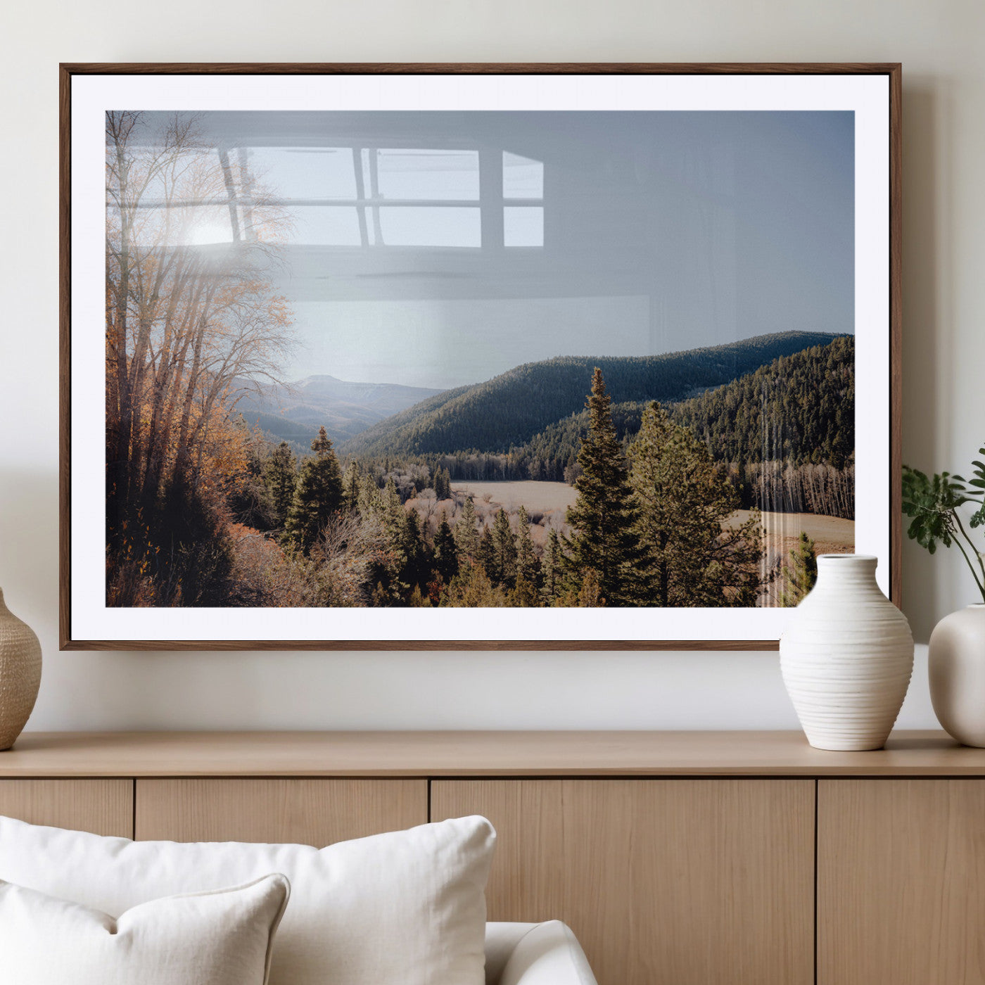 A scenic mountain valley with pine trees and autumn foliage under a clear sky, bathed in golden sunlight, creating a peaceful and rustic landscape.