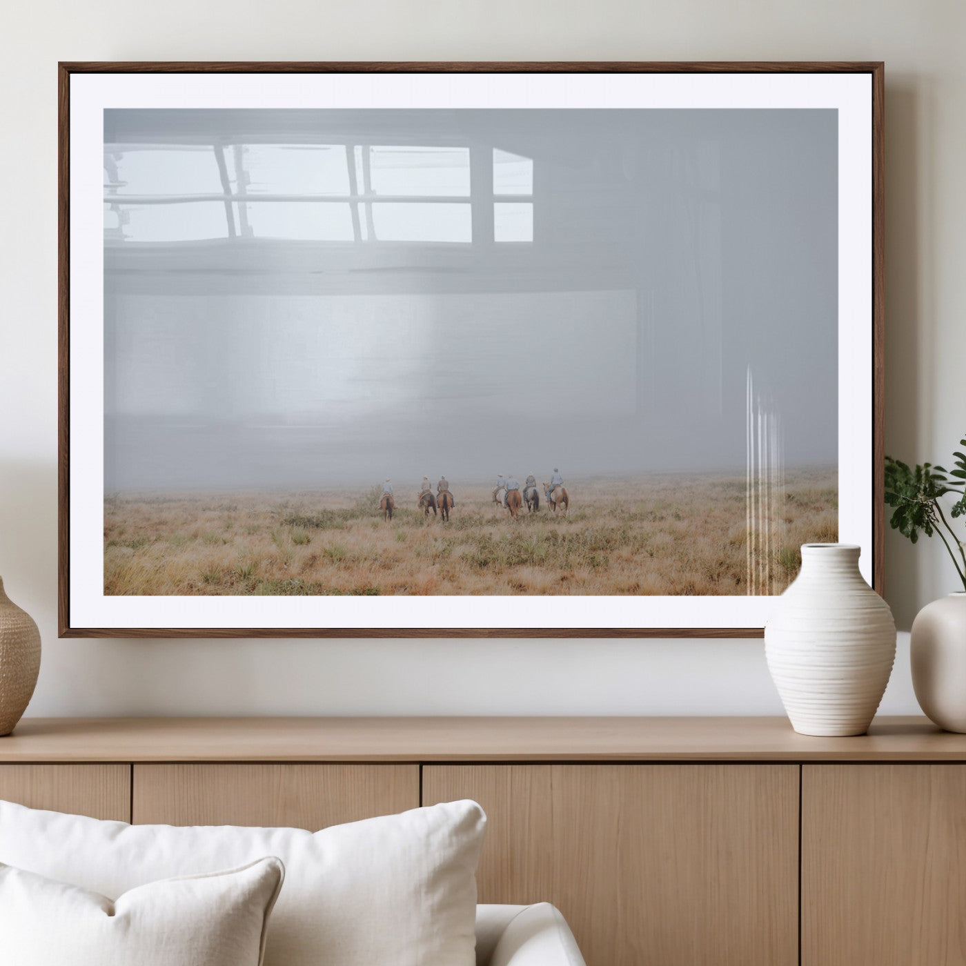 A group of horseback riders moving through a fog-shrouded field, evoking a calm Western scene with golden grasses and soft horizons.