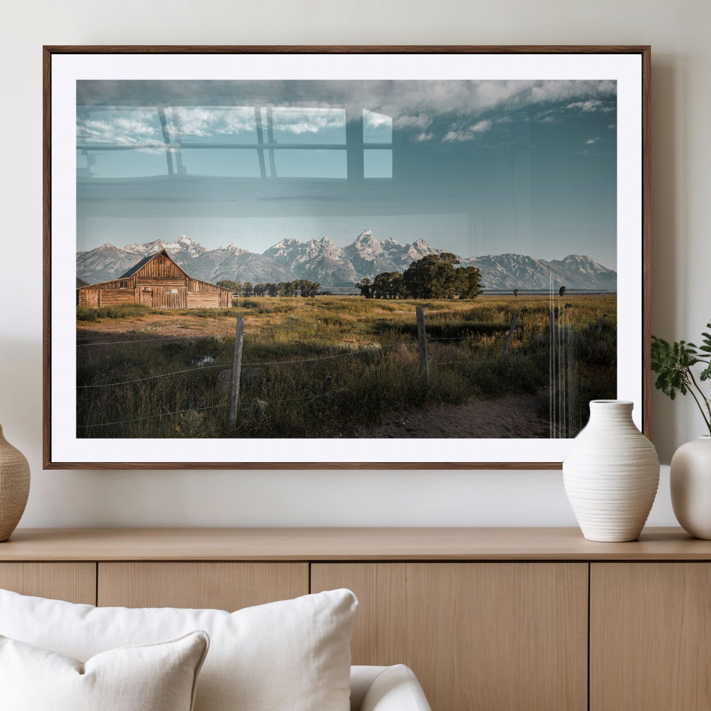 A rustic farmhouse with a wooden barn set against majestic mountain peaks under a soft blue sky, evoking peaceful countryside charm.