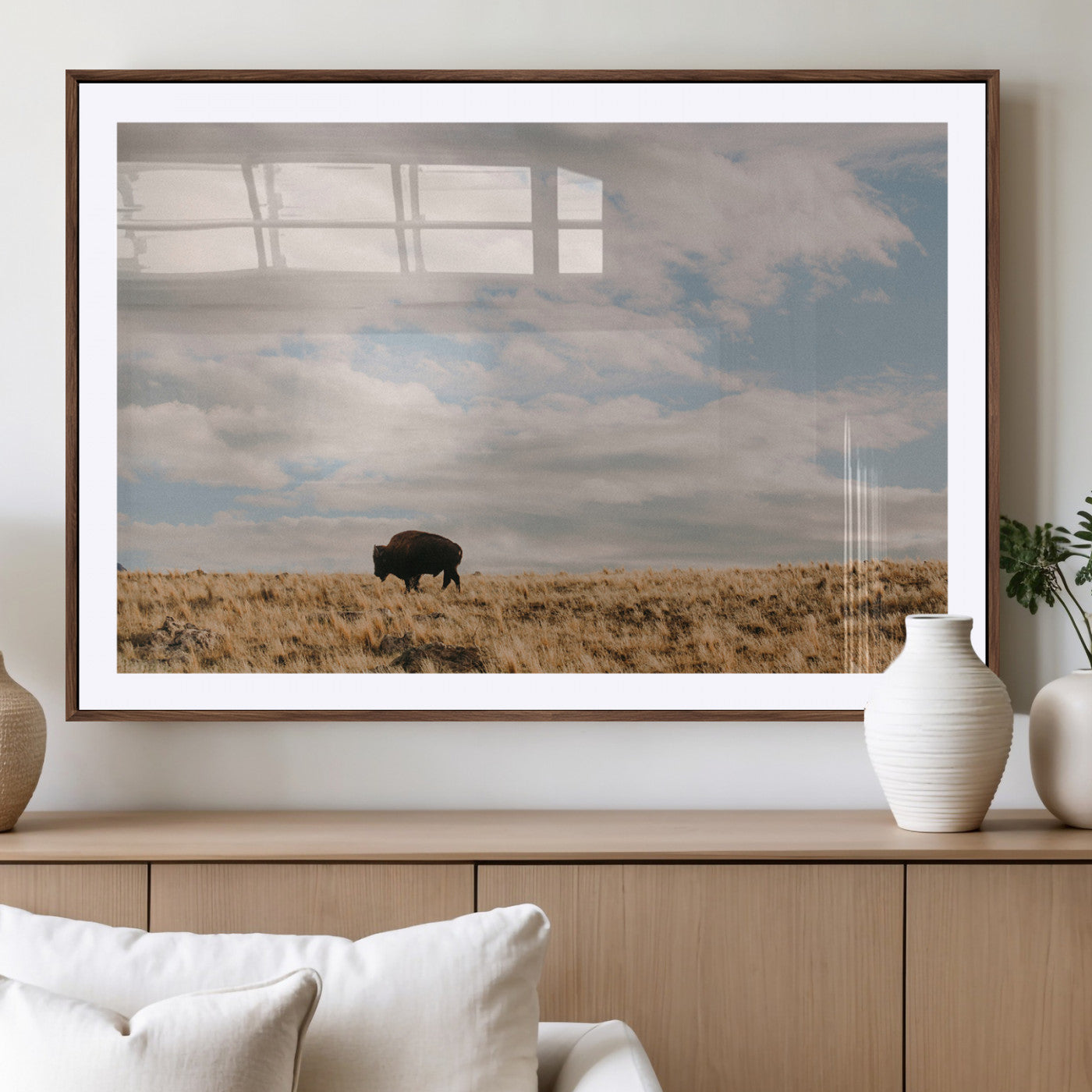 A solitary bison walking across a golden prairie under a vast, cloud-filled sky, evoking a peaceful, rustic western landscape for home decor.
