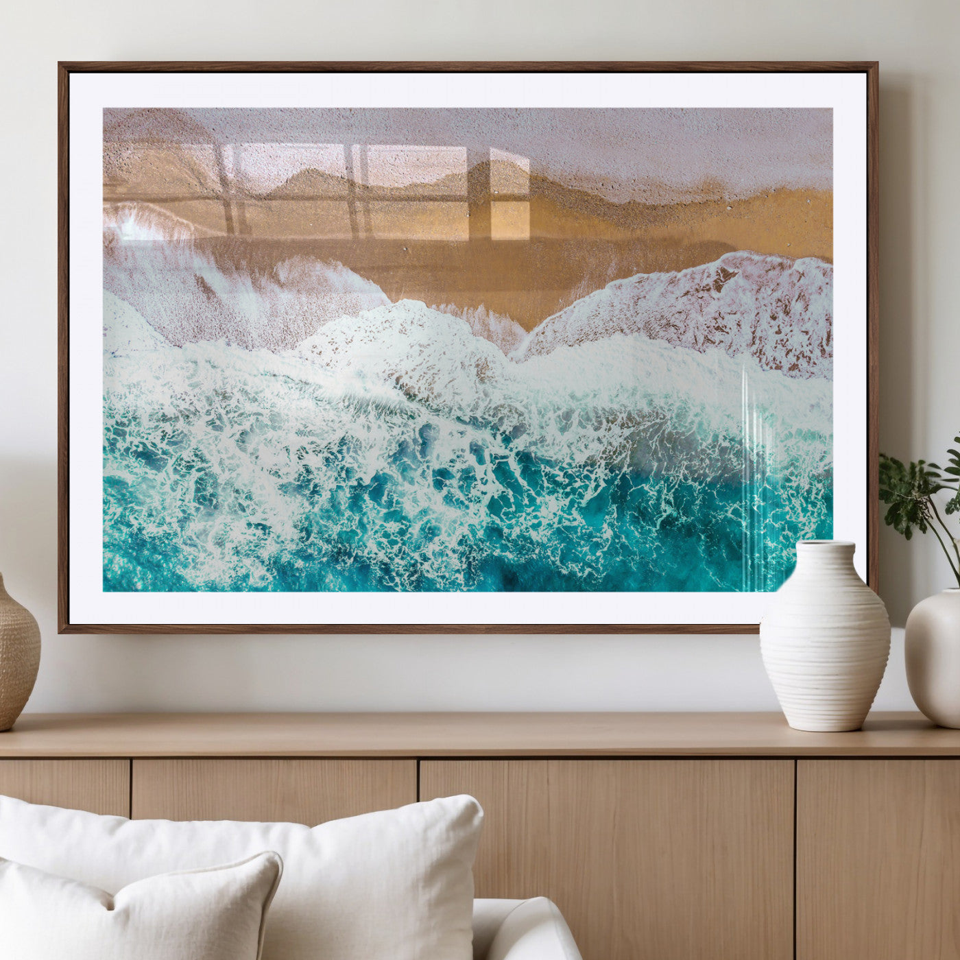 Aerial view of ocean waves crashing onto a sandy beach, with turquoise water and foamy white surf, creating a serene coastal aesthetic for home decor.