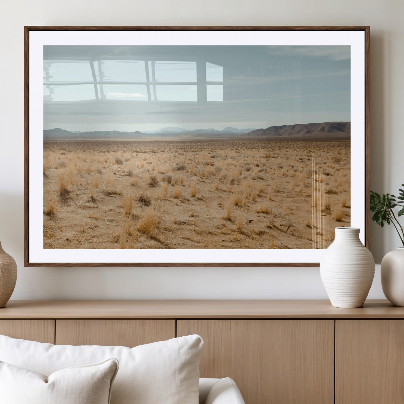 Expansive desert landscape with scattered dry grass and distant mountain range under a pale blue sky – Wall Art Canvas Print.