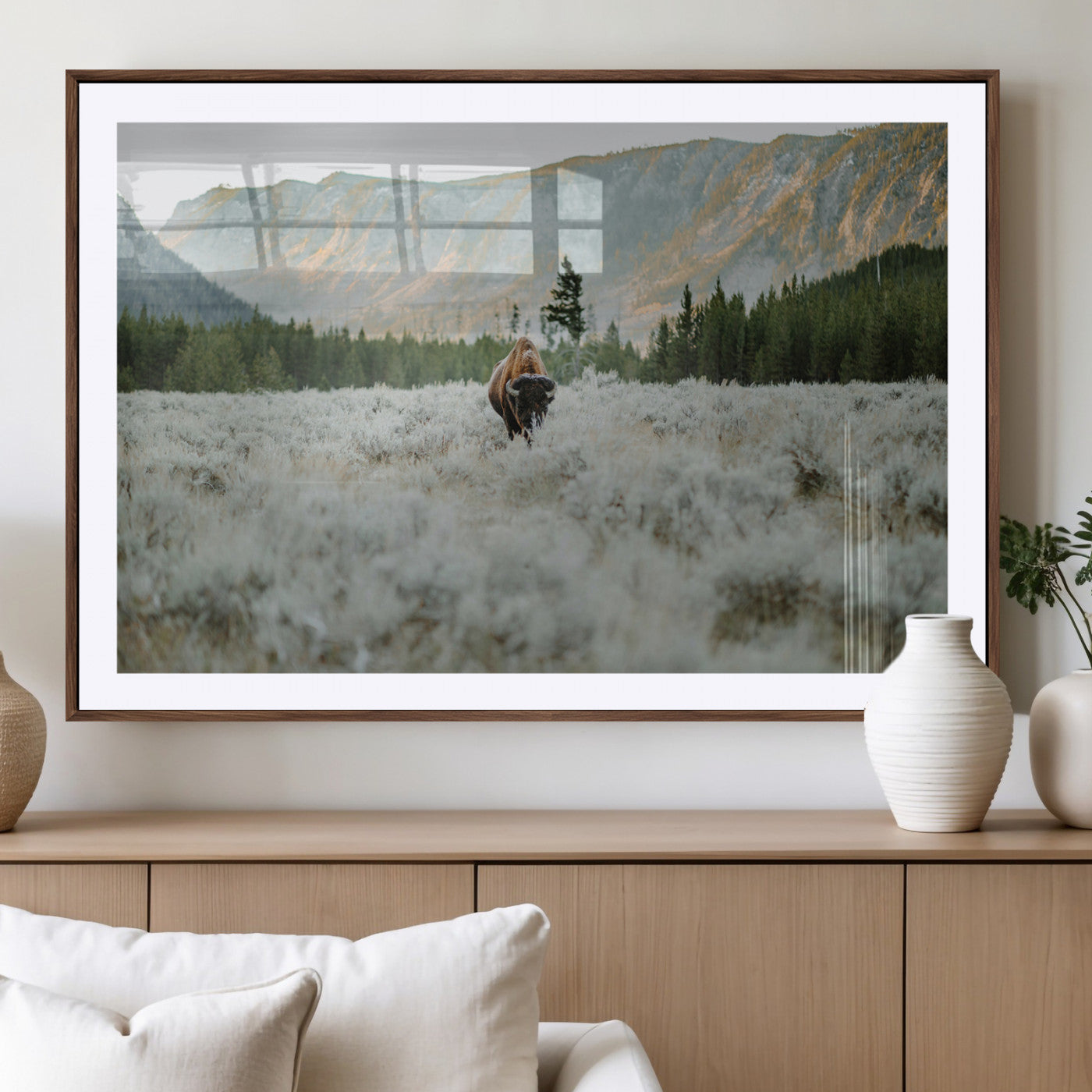 Lone bison standing in a frosted sagebrush field with a pine forest and rugged mountain range in the background under soft morning light – Wall Art Canvas Print.