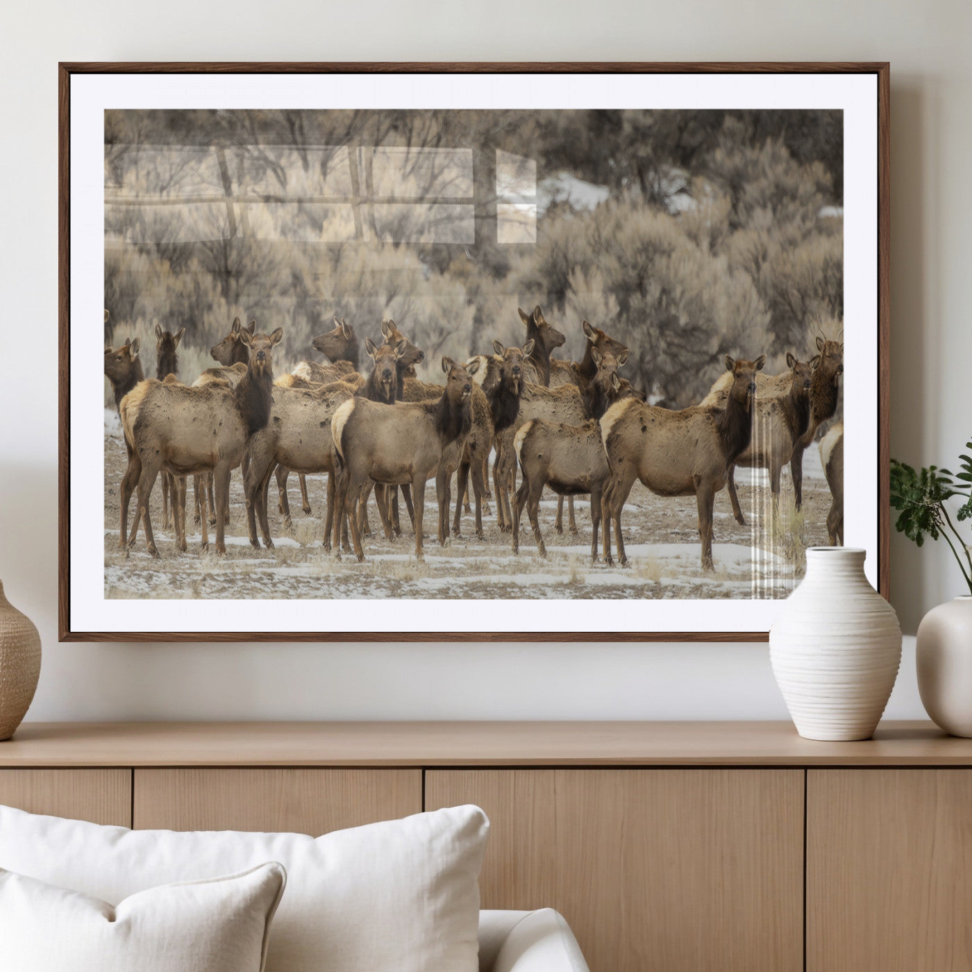 A stunning wall art canvas print featuring a large herd of elk standing together in a natural winter landscape with muted earthy tones and soft background foliage, perfect for rustic or nature-inspired home decor.
