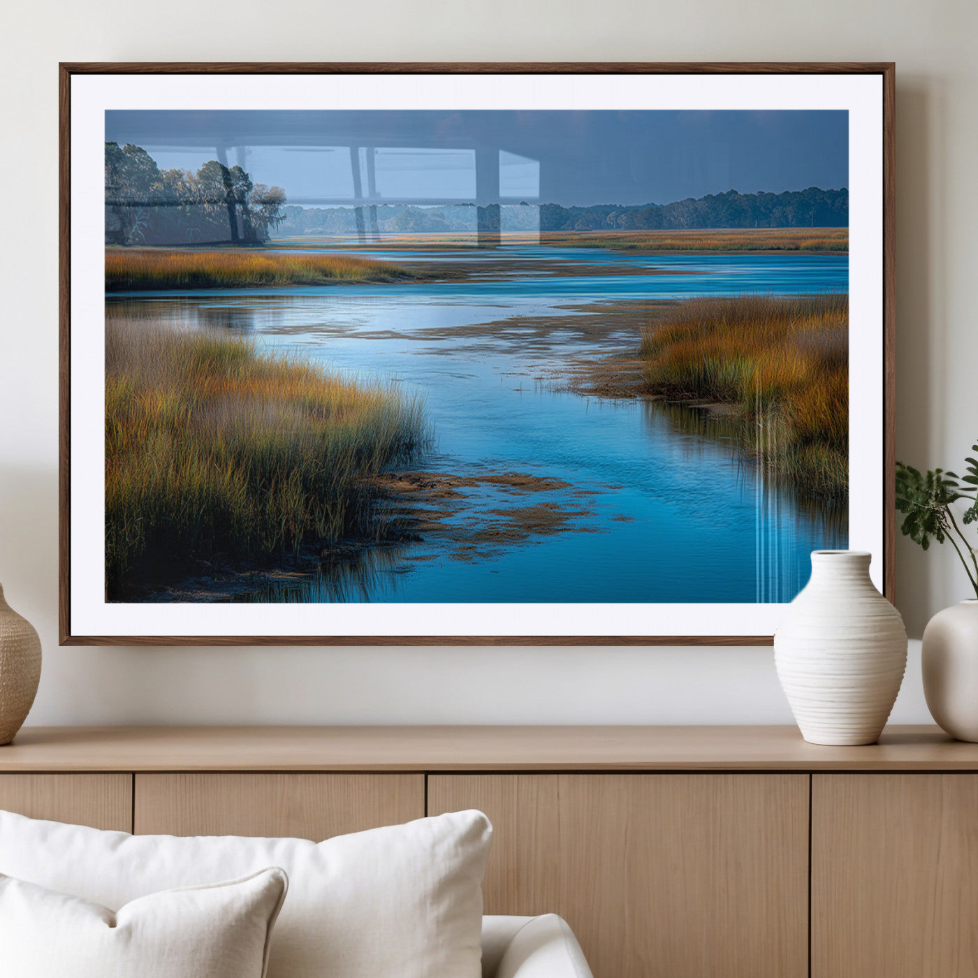 A peaceful marshland scene with calm blue water reflecting the surrounding grasses and trees, capturing the beauty of nature in a serene landscape.