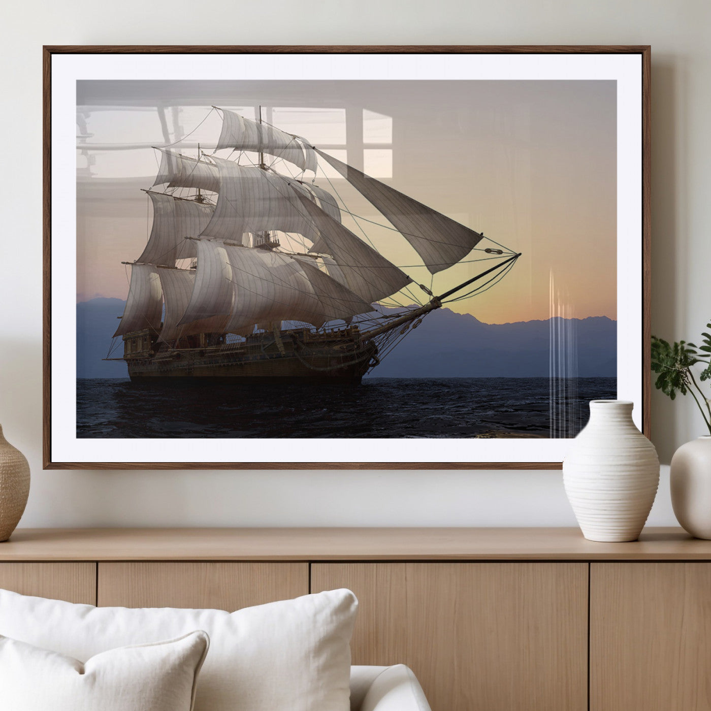 Majestic tall ship with full sails gliding across the ocean at sunset, with mountain silhouettes in the background – Wall Art Canvas Print.