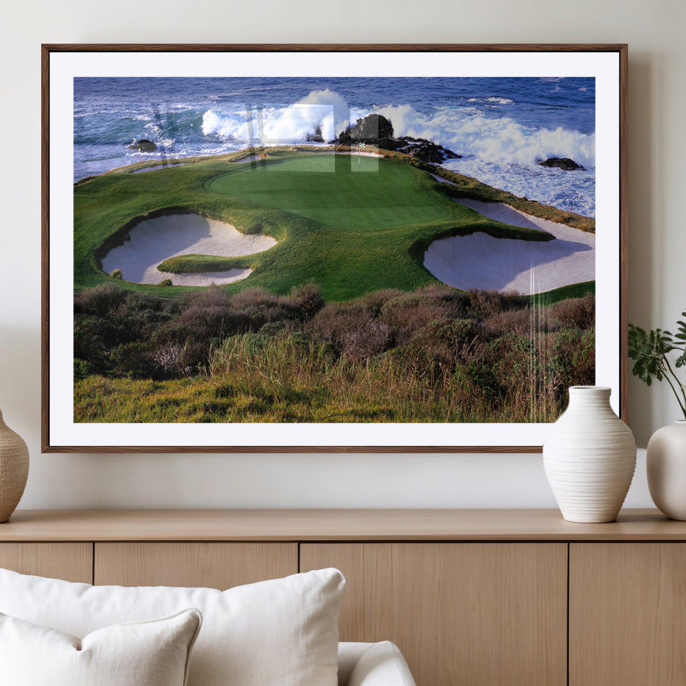 A scenic golf course located by the ocean, featuring a well-manicured green surrounded by sand traps and powerful ocean waves crashing on the shore.