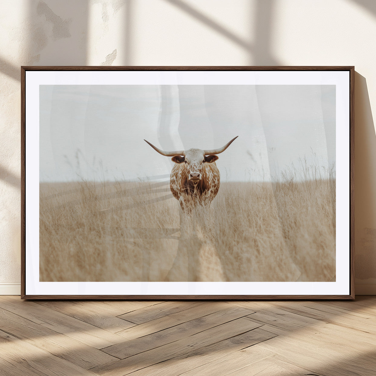 Texas Longhorn bull standing alone in dry grass with neutral tones, ideal for rustic western or cowboy-themed wall decor.