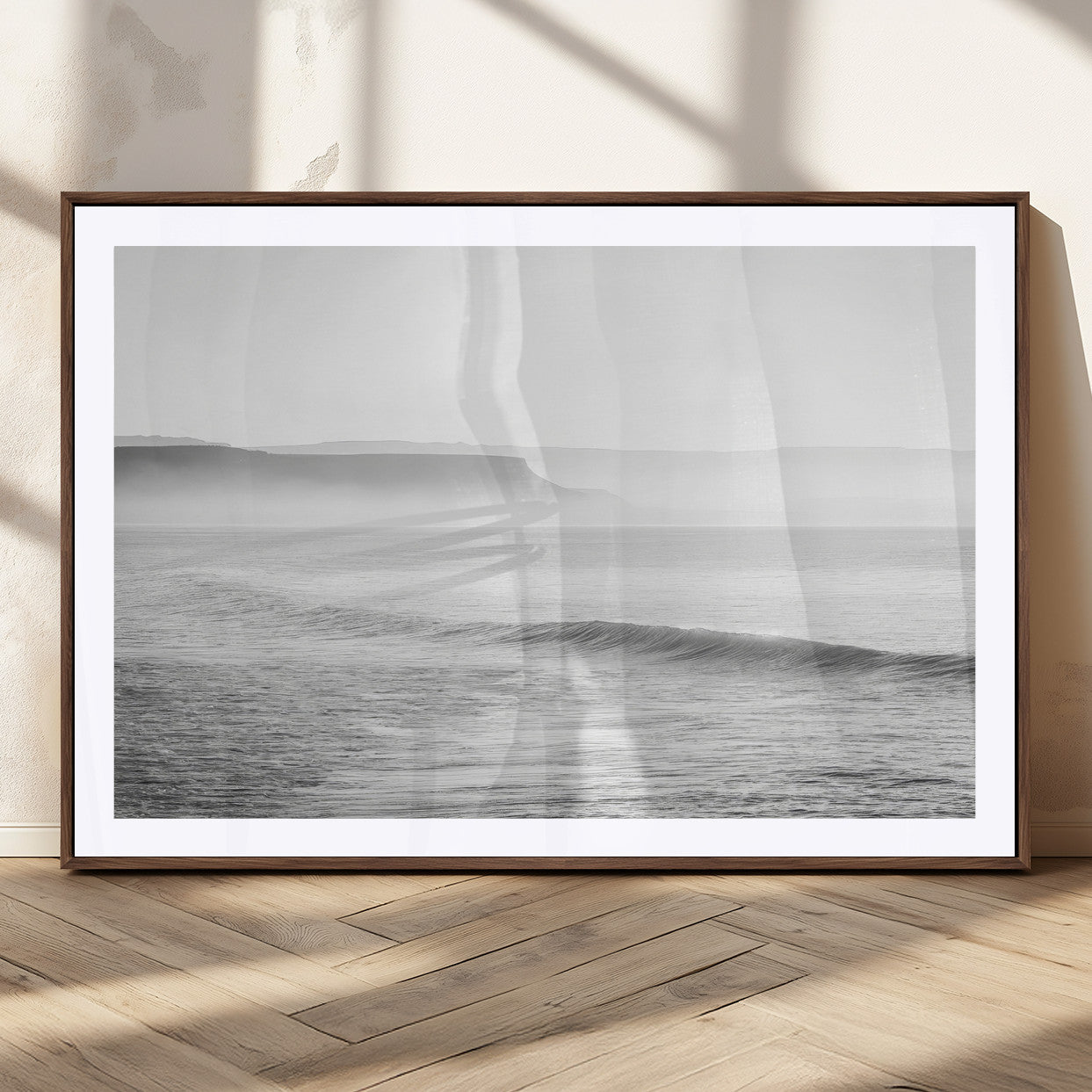 A black and white minimalist seascape featuring soft rolling waves and misty distant cliffs, creating a serene and timeless coastal atmosphere.