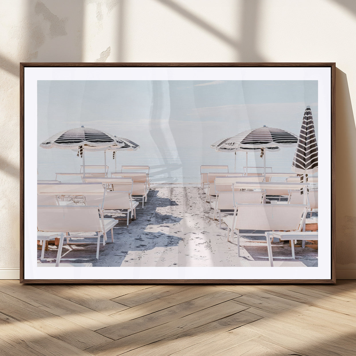 A serene minimalist beach scene featuring striped umbrellas, soft pastel sand, and an elegant lounge setup, creating a tranquil and stylish coastal retreat.