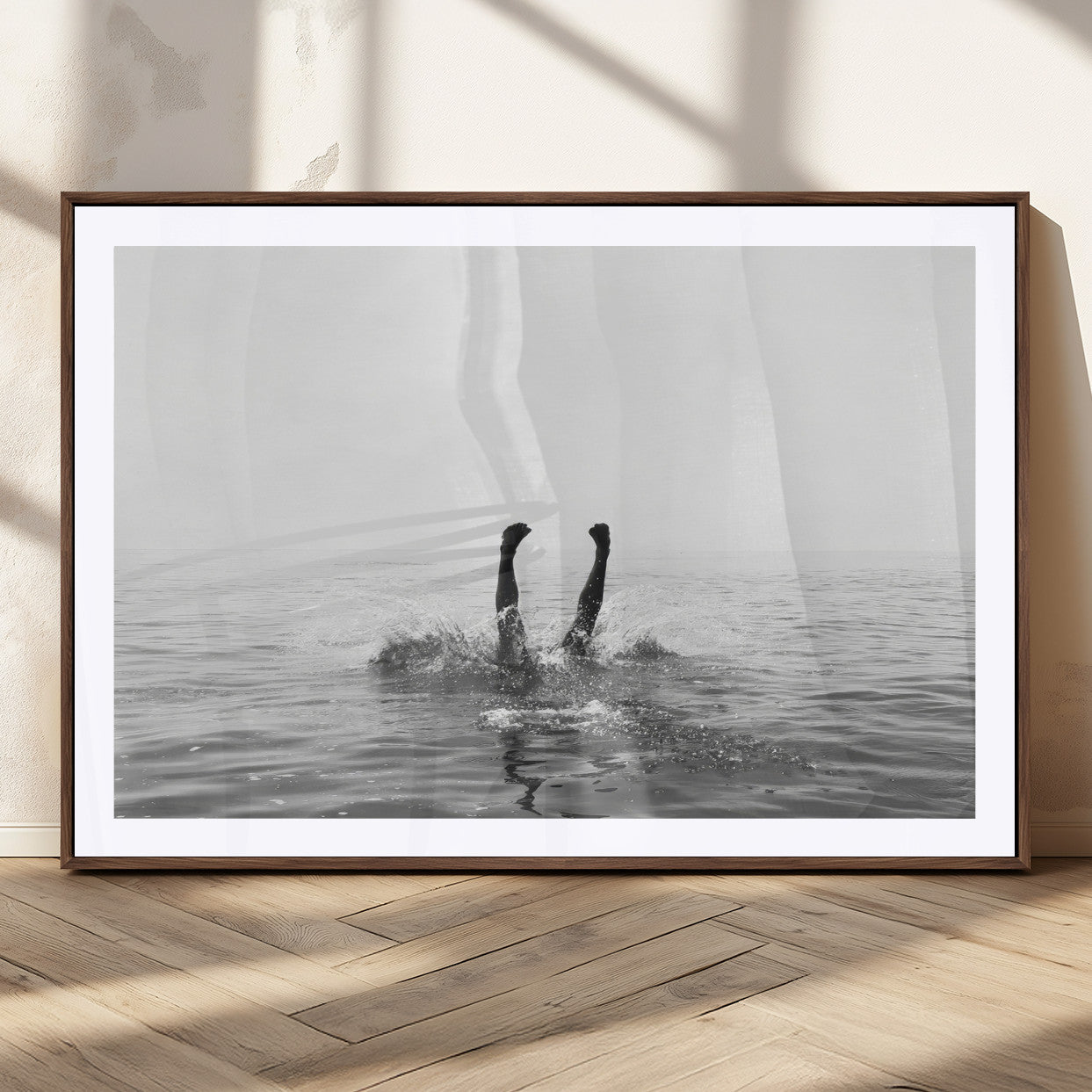 A black and white minimalist water scene capturing a playful splash as a swimmer dives upside down, creating a carefree and artistic aquatic aesthetic.