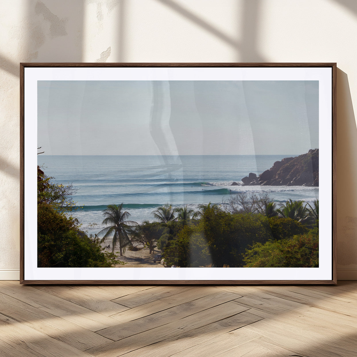 View of calm ocean waves with palm trees and a tropical coastline, ideal for coastal boho or beach-themed wall decor.