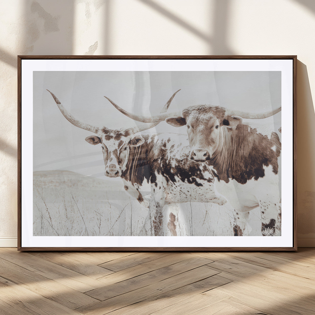 Two longhorn cattle standing in a dry grassy field with neutral tones, creating a rustic and farmhouse-inspired Western aesthetic.