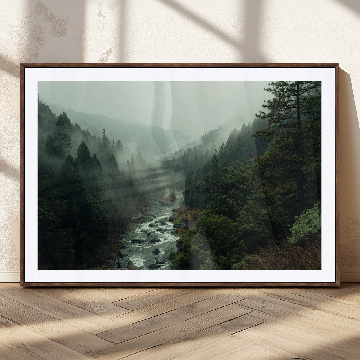 Misty forest with a winding river flowing through lush green mountains, creating a tranquil and moody wilderness landscape.