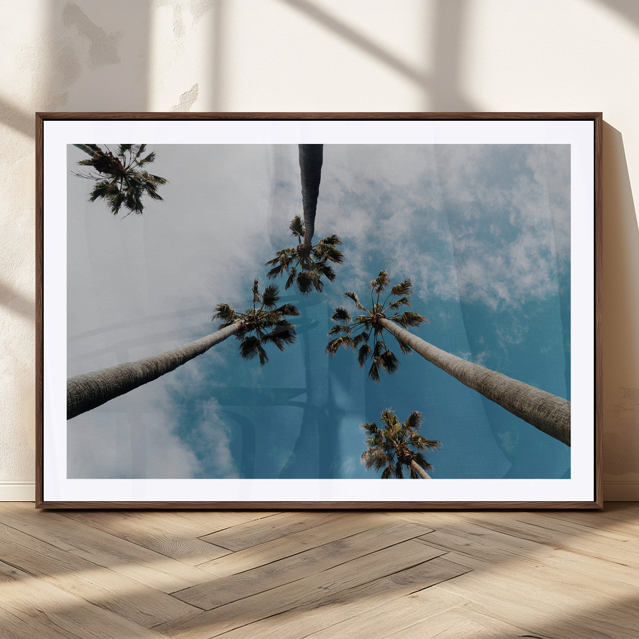 Looking up at tall palm trees against a bright blue sky with scattered clouds, creating a tropical and airy atmosphere for modern home decor.