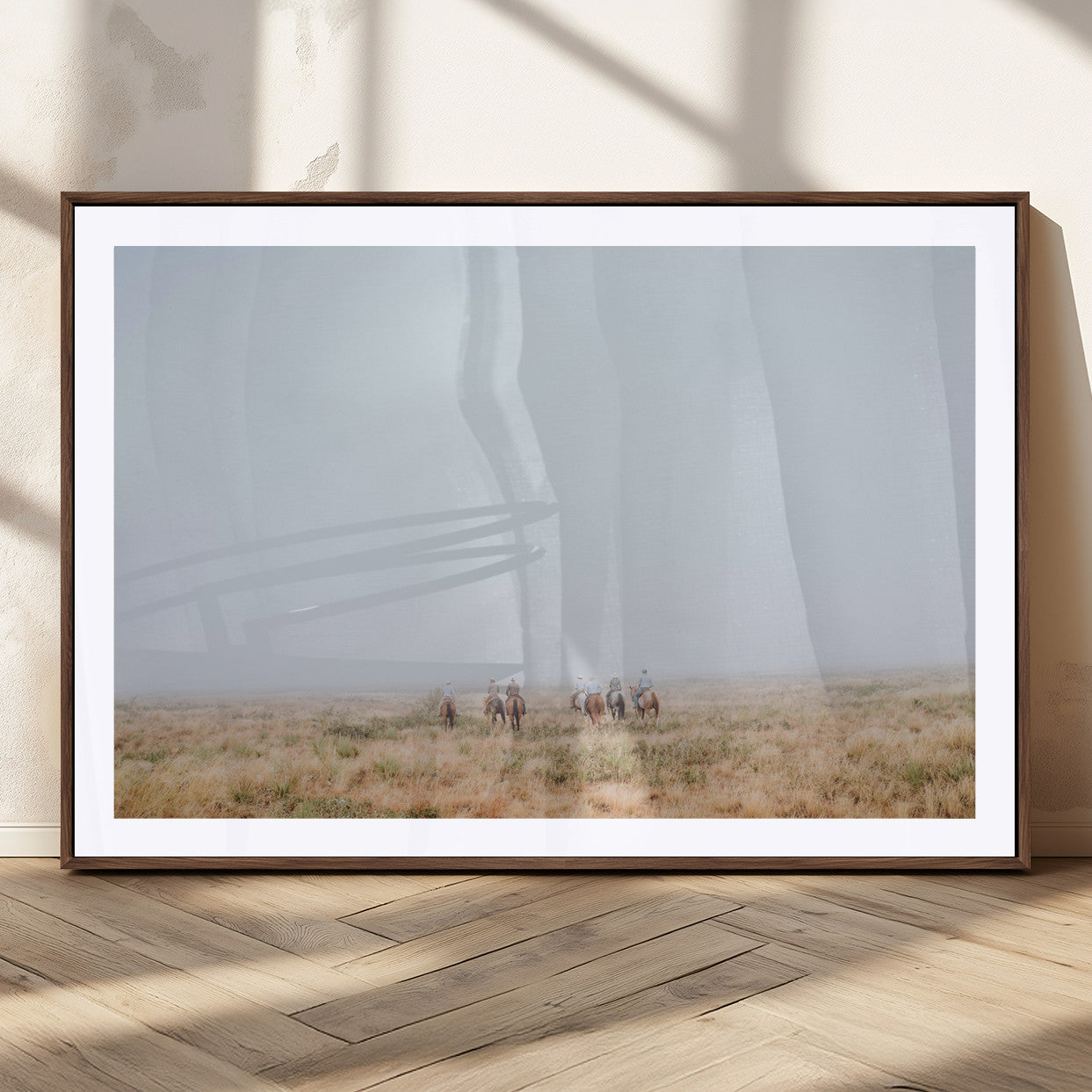 A group of horseback riders moving through a fog-shrouded field, evoking a calm Western scene with golden grasses and soft horizons.