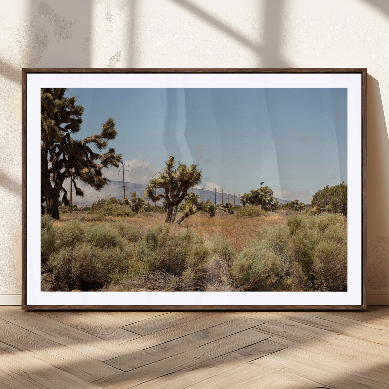Scenic desert landscape with Joshua trees, dry grass, and distant mountains under a clear blue sky, perfect for southwestern and rustic decor.