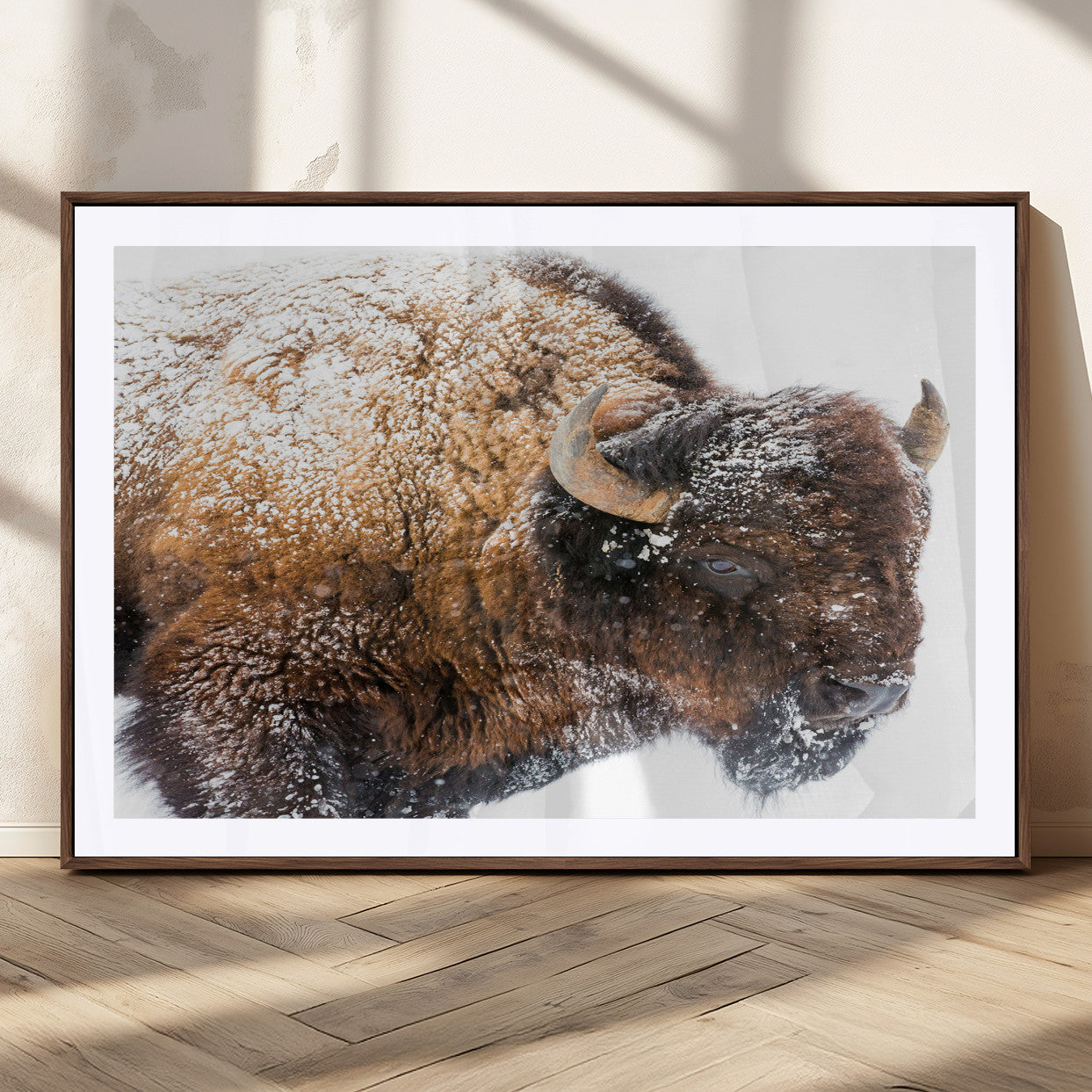 Close-up photograph of a bison covered in snow, highlighting its thick fur and powerful presence, set against a white winter backdrop, ideal for rustic decor.