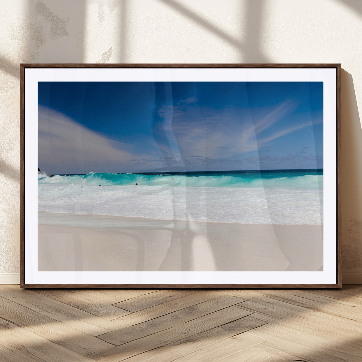 Turquoise waves crash onto a pristine white sand beach under a vivid blue sky with wispy clouds, creating a peaceful and refreshing coastal scene.
