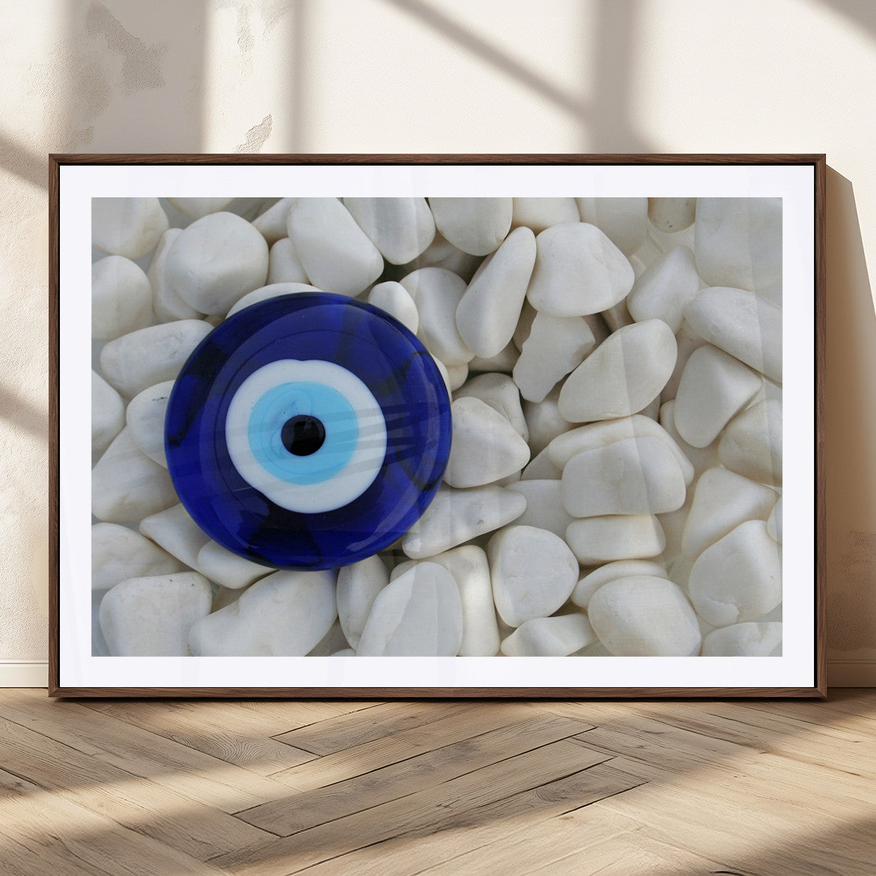 A close-up of a blue evil eye charm placed on white pebbles, symbolizing protection and good luck.