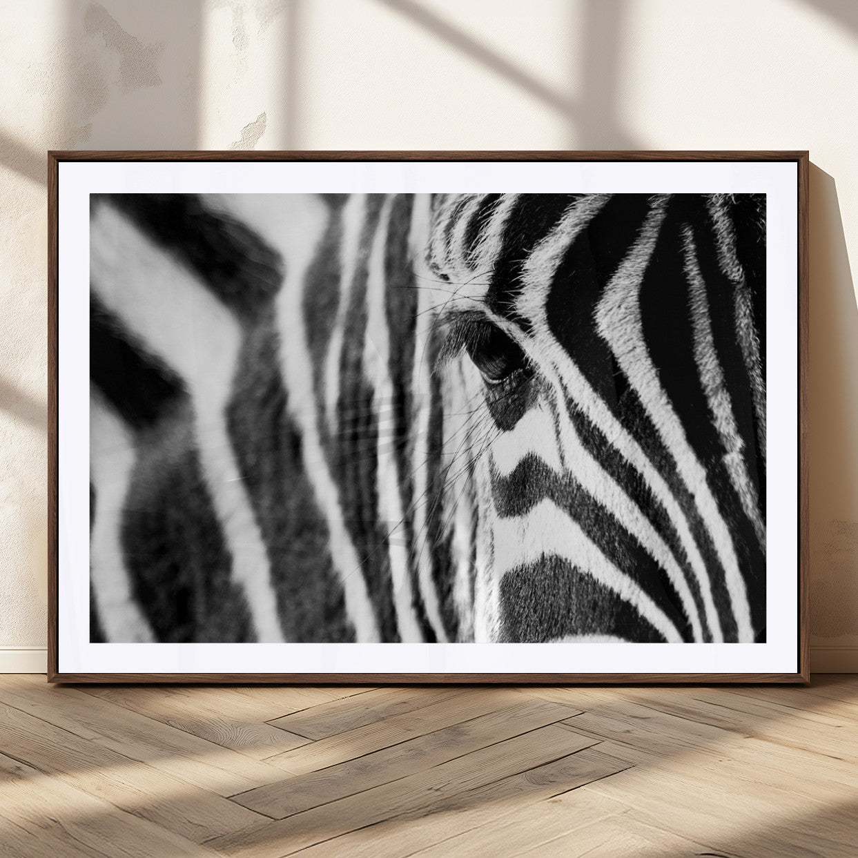 A close-up black and white photograph of a zebra's eye, showcasing the intricate patterns of its stripes in sharp detail.