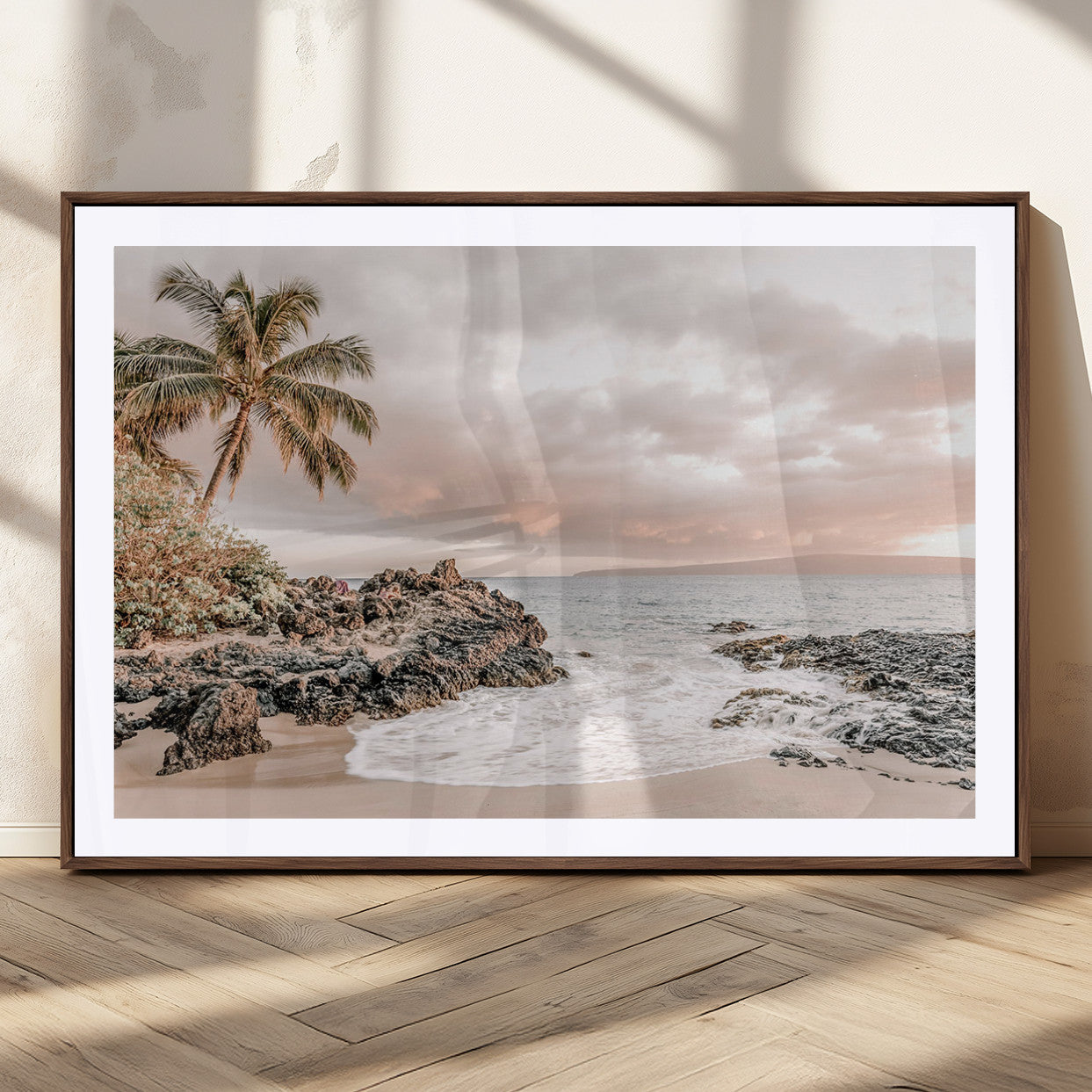 A peaceful beach scene with a palm tree and rocks, soft waves washing onto the shore under a soft pastel sky at sunset.