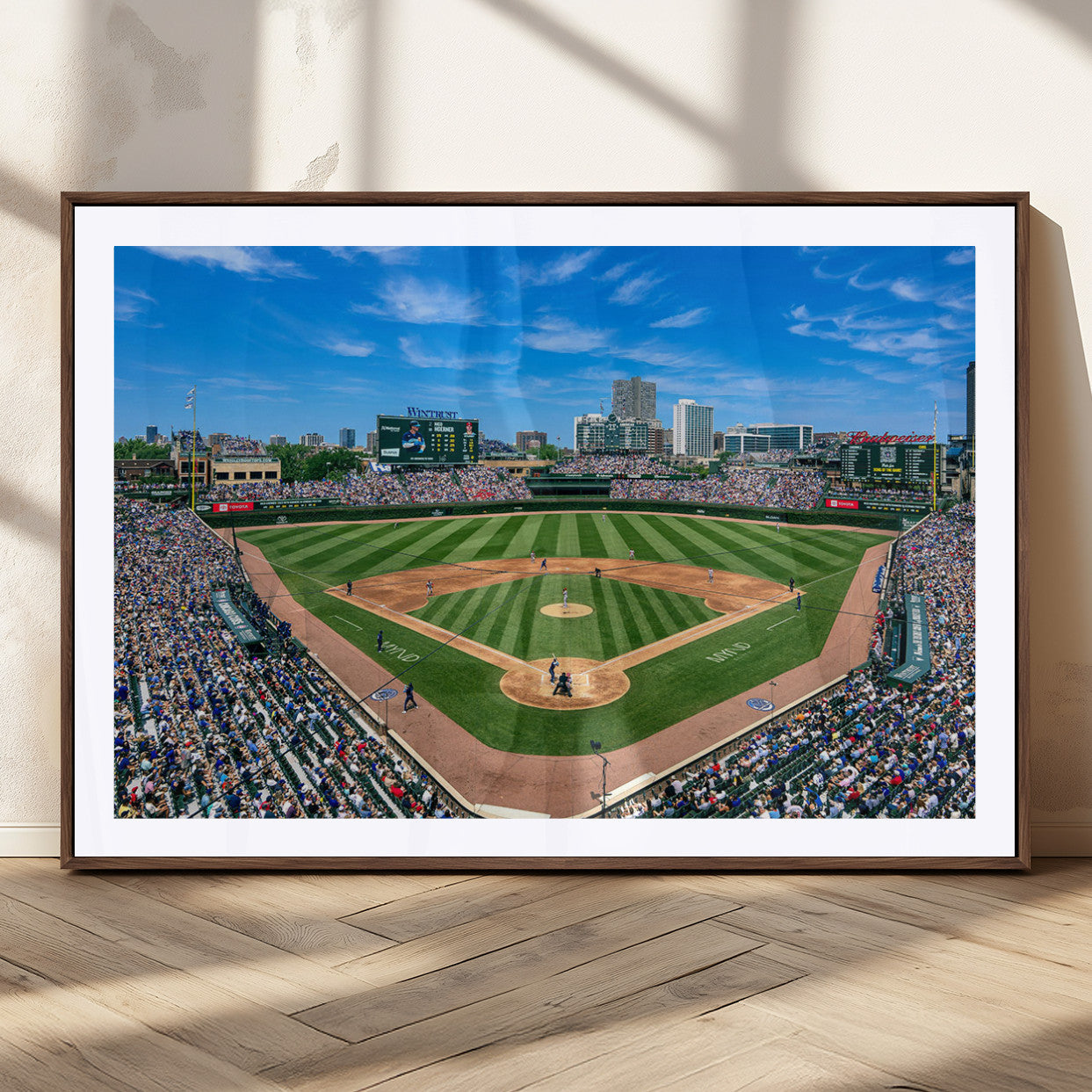 A wide-angle shot of a baseball field filled with spectators, with players on the field and the iconic Wrigley Field scoreboard in the background.