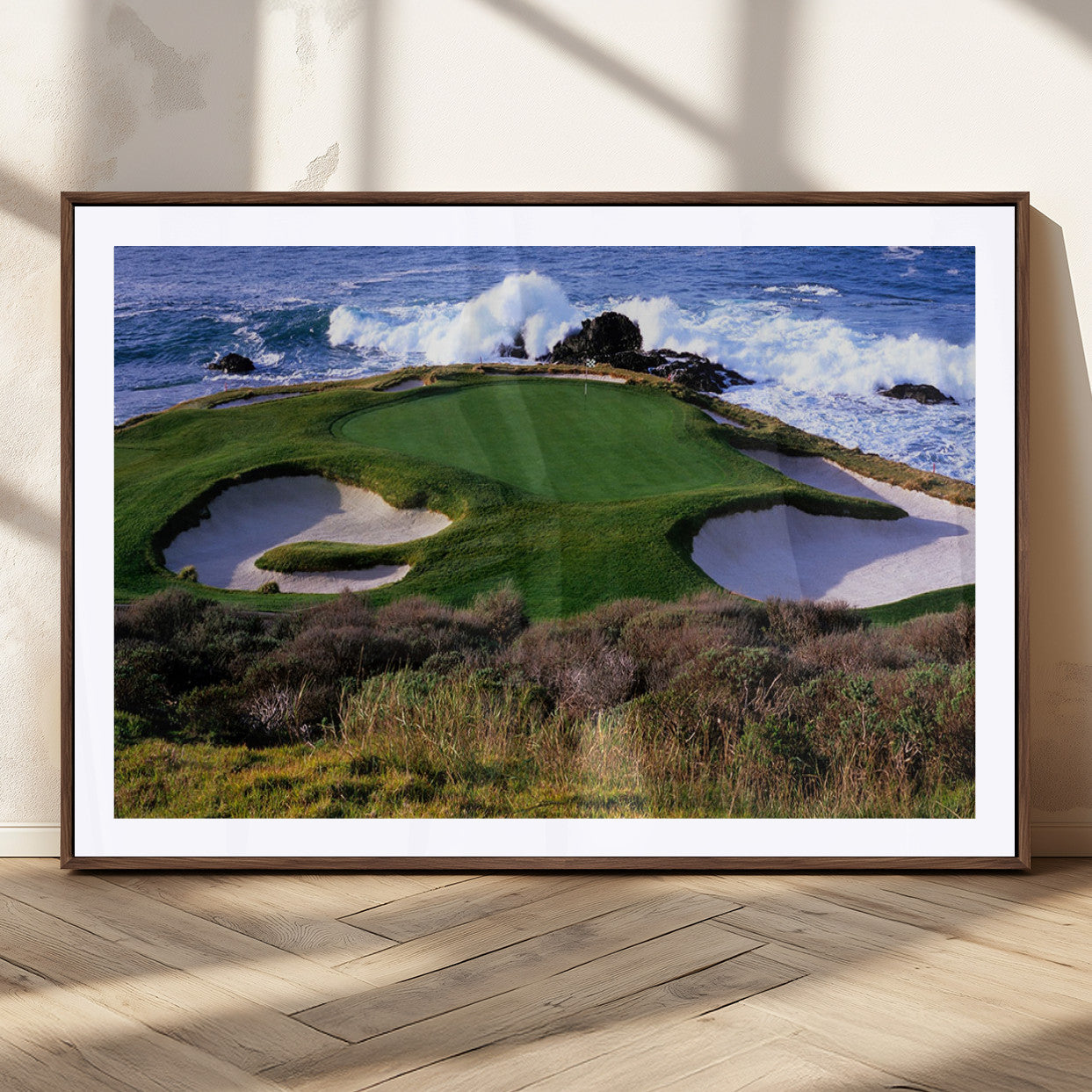 A scenic golf course located by the ocean, featuring a well-manicured green surrounded by sand traps and powerful ocean waves crashing on the shore.