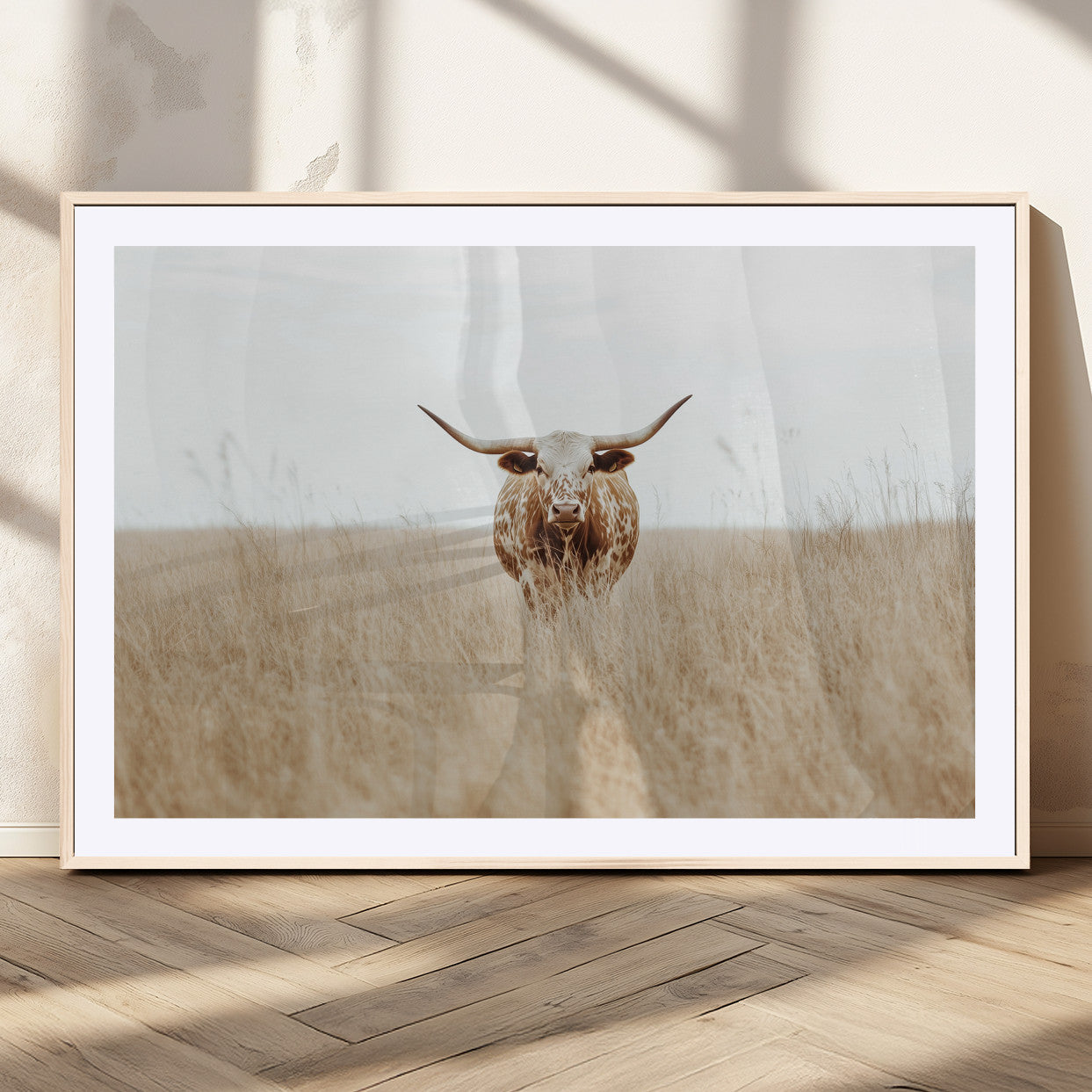 Texas Longhorn bull standing alone in dry grass with neutral tones, ideal for rustic western or cowboy-themed wall decor.