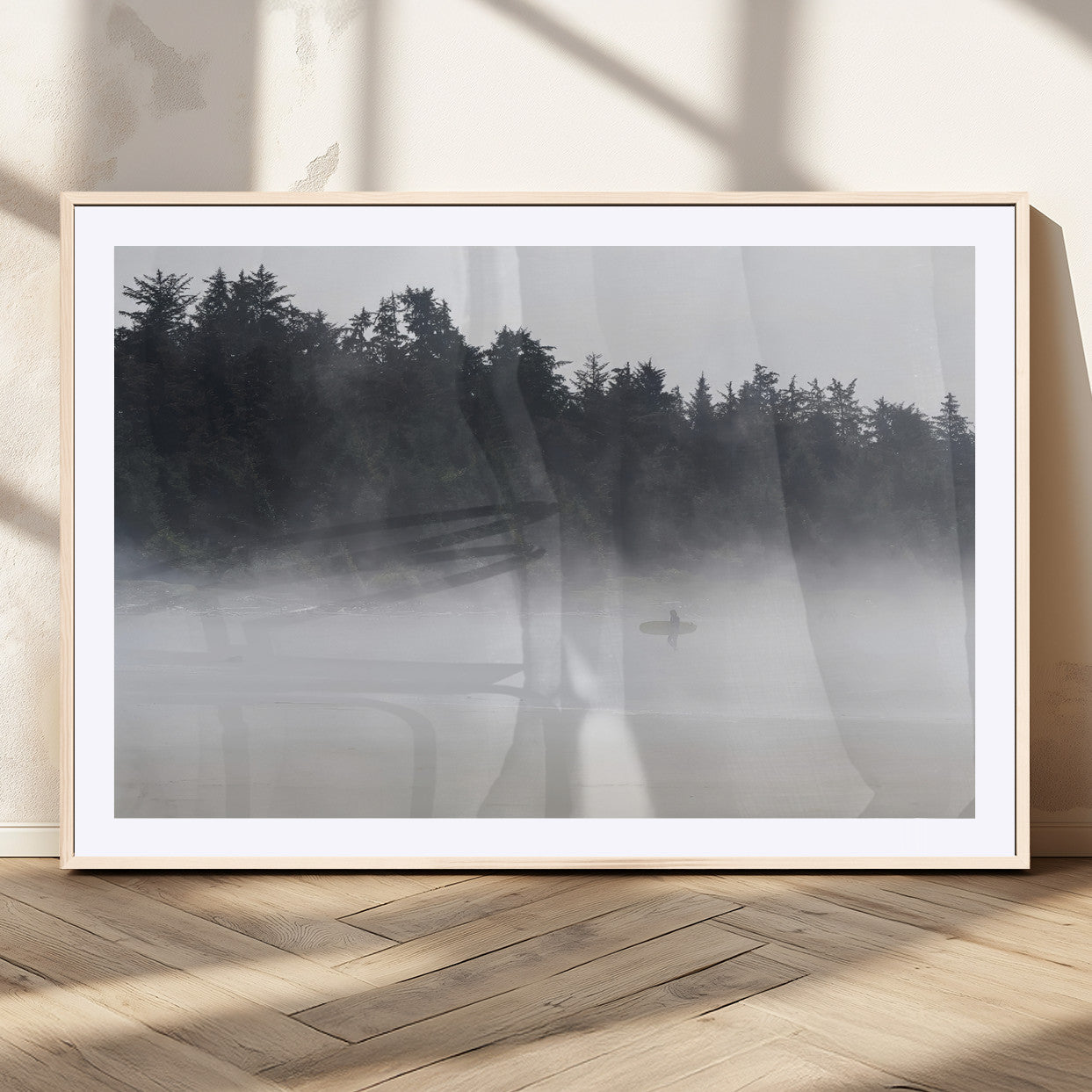 A lone surfer carrying a board through a misty shoreline, surrounded by dense trees and fog, creating a peaceful and mysterious coastal scene.