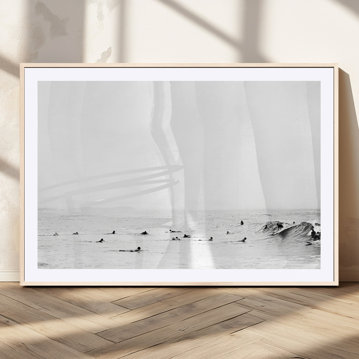 A group of surfers floating in the ocean, waiting for waves under a vast, moody sky, captured in black and white.