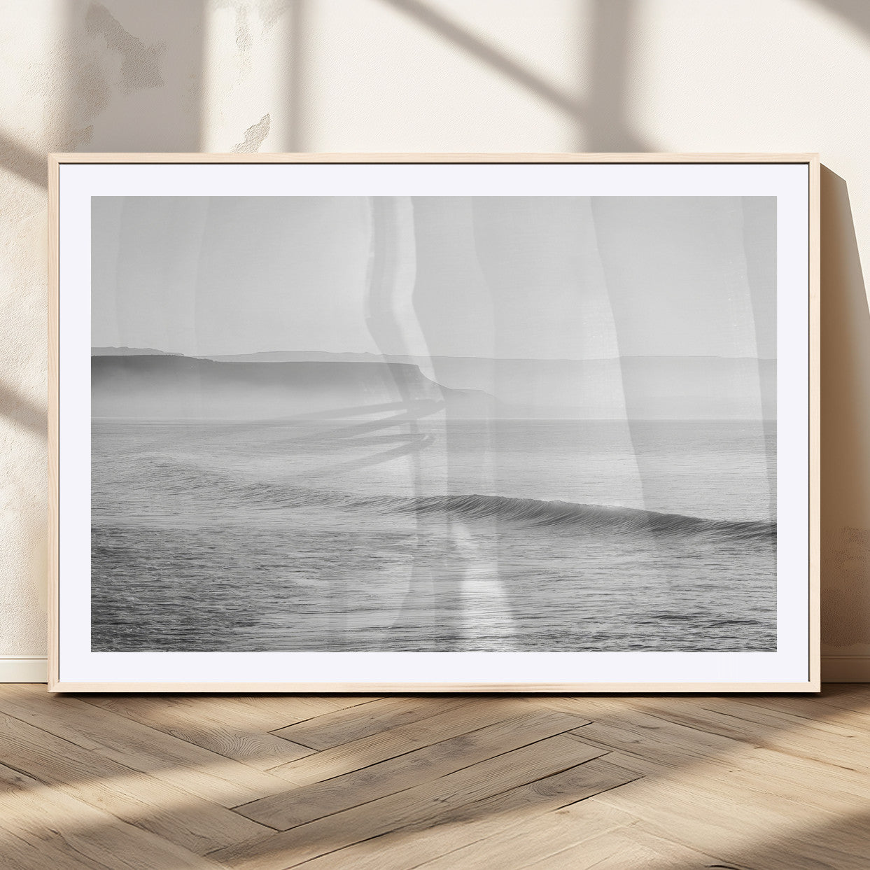 A black and white minimalist seascape featuring soft rolling waves and misty distant cliffs, creating a serene and timeless coastal atmosphere.