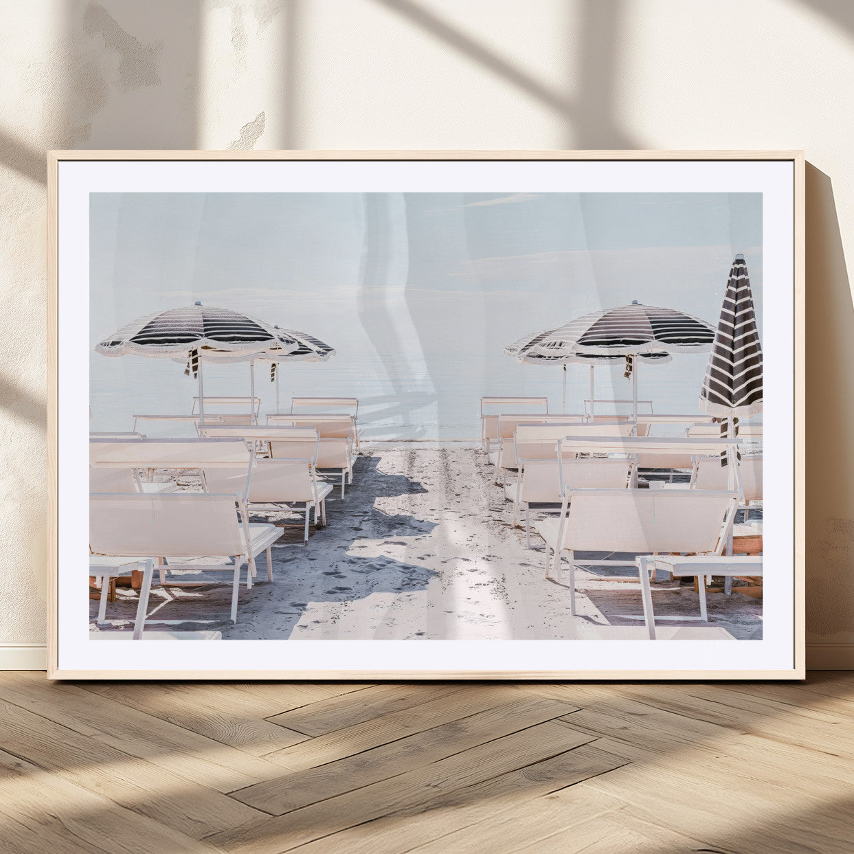 A serene minimalist beach scene featuring striped umbrellas, soft pastel sand, and an elegant lounge setup, creating a tranquil and stylish coastal retreat.