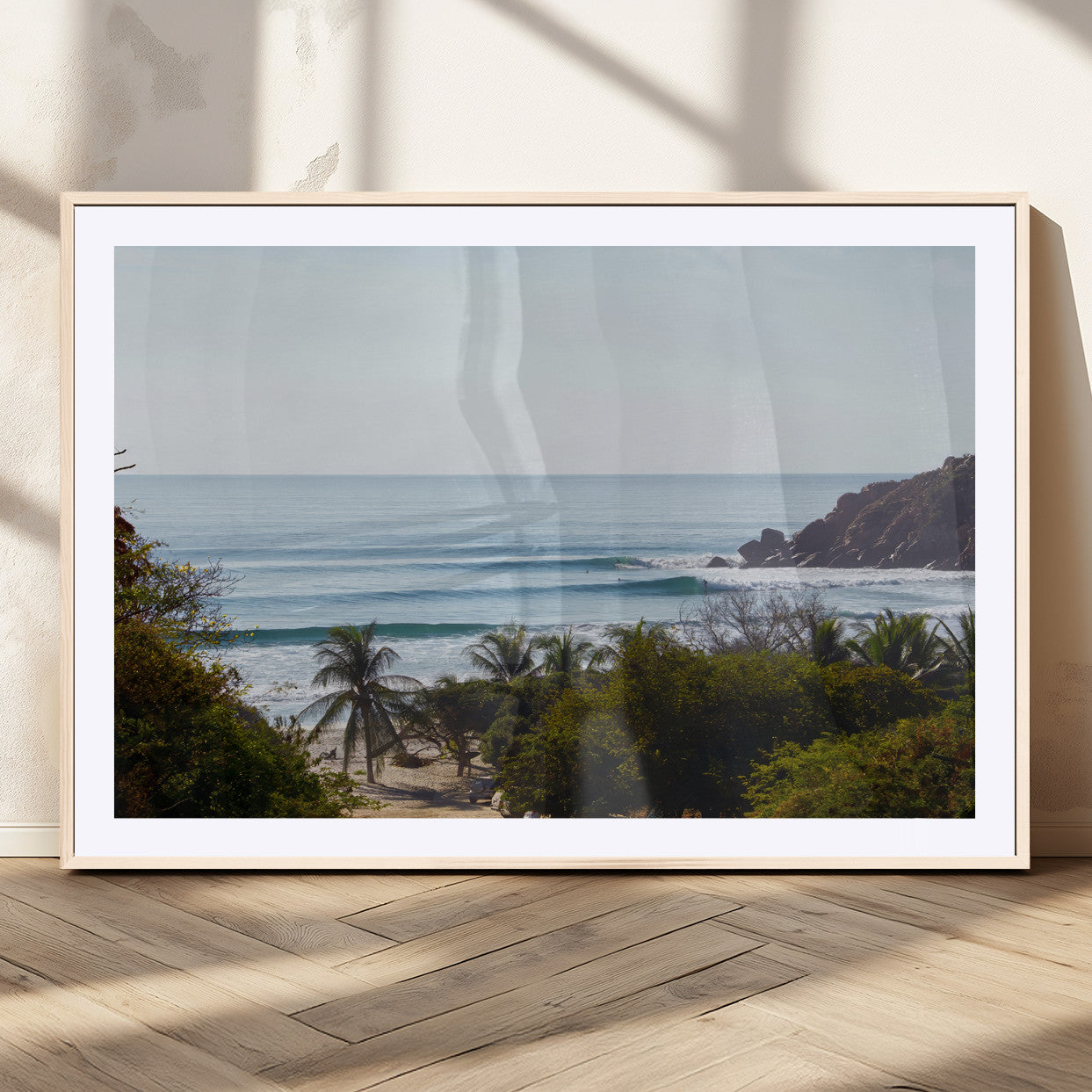 View of calm ocean waves with palm trees and a tropical coastline, ideal for coastal boho or beach-themed wall decor.
