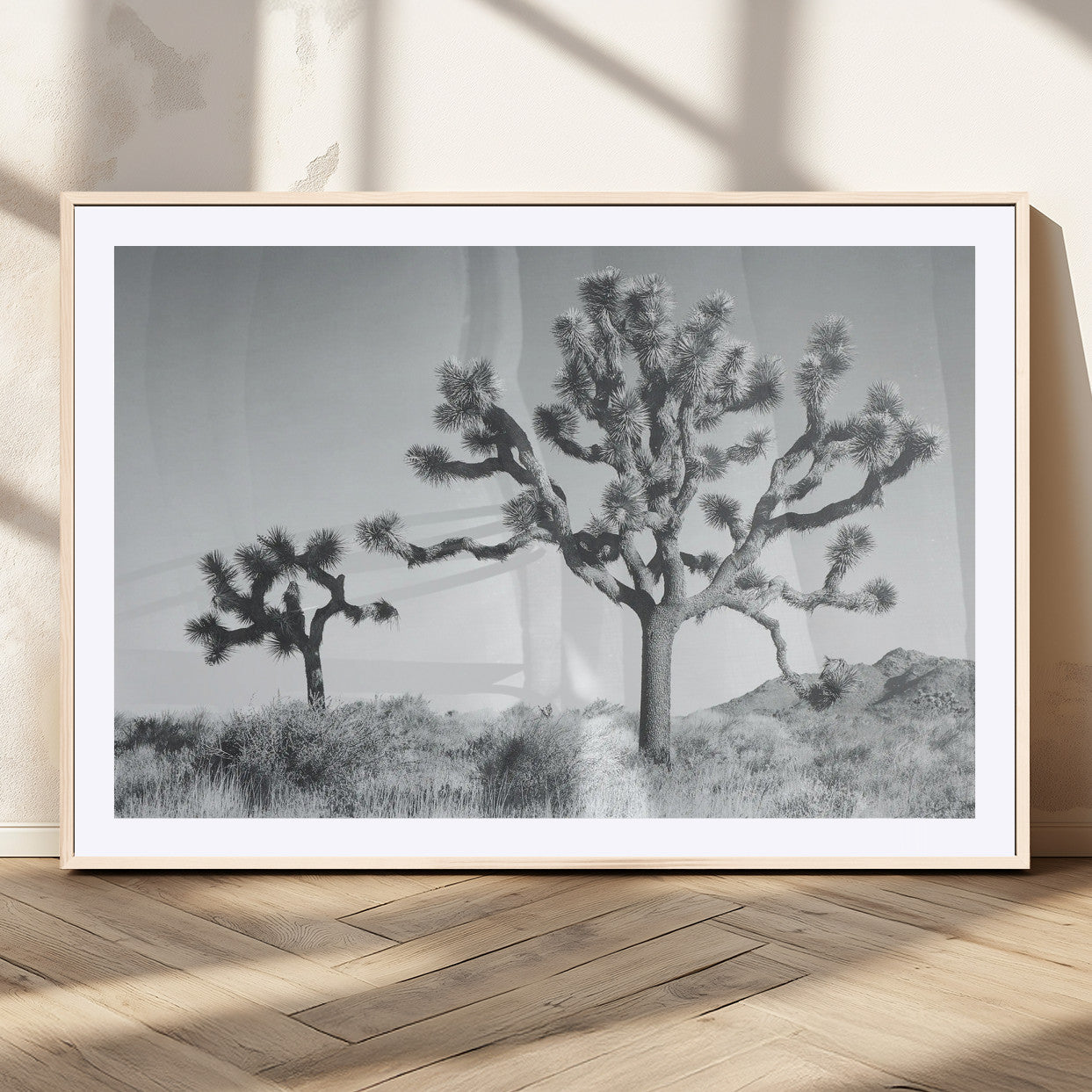 Two Joshua trees in a black and white desert landscape with distant hills, ideal for boho or rustic interior wall styling.