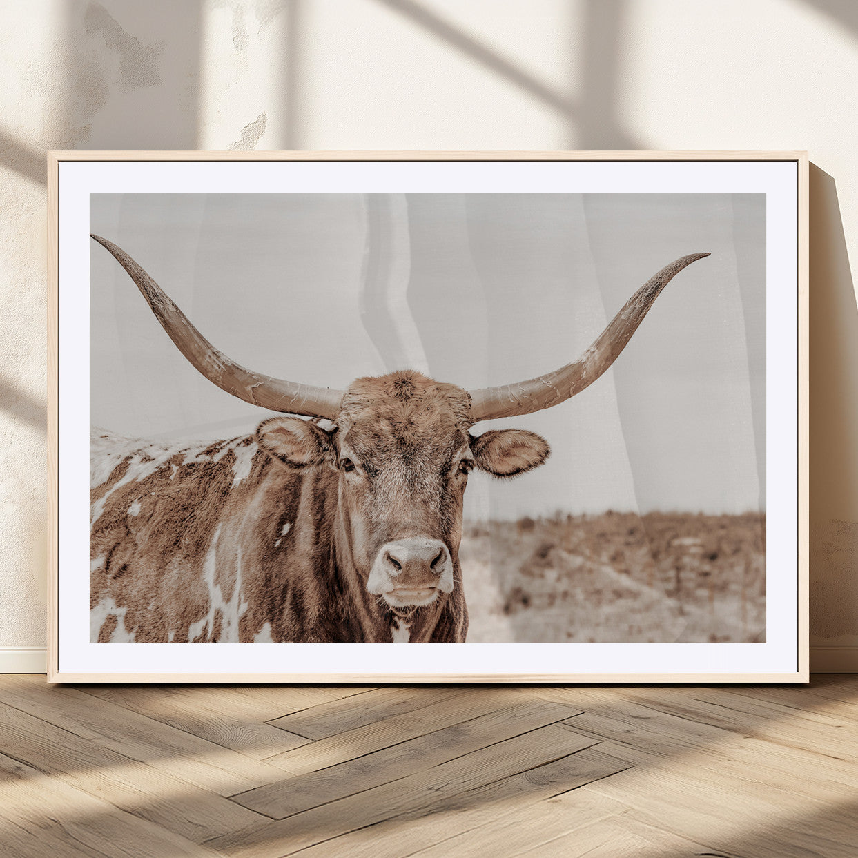 A longhorn cow in soft beige desert tones, standing calmly in open land, perfect for neutral western or rustic farmhouse interiors.
