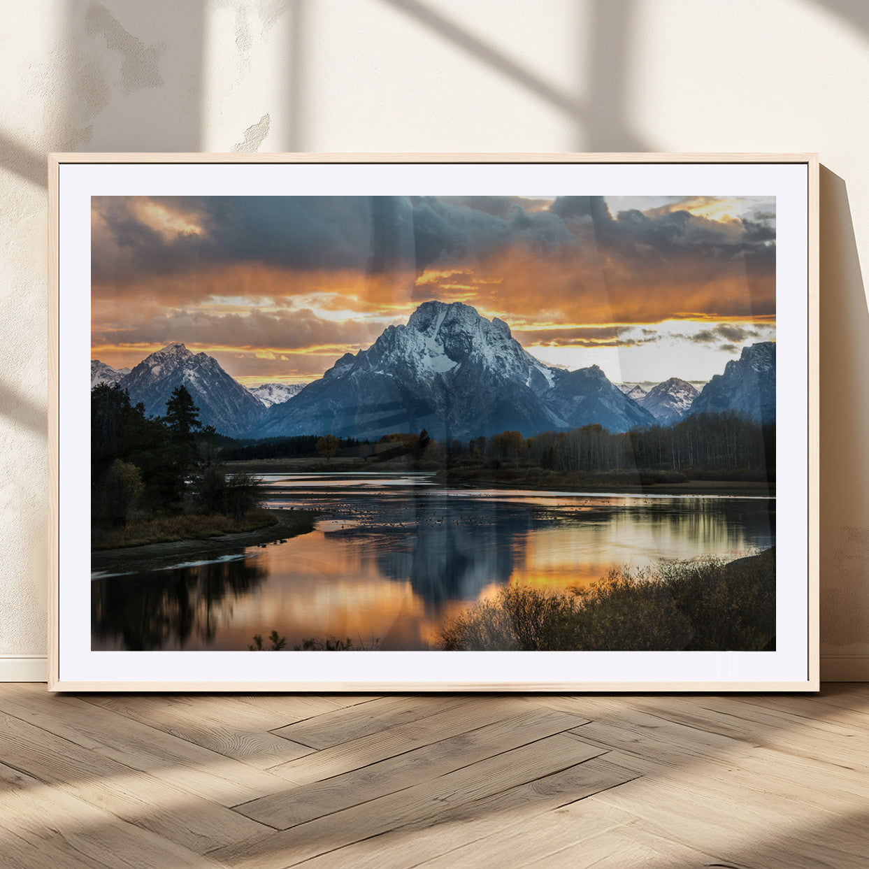Snow-capped mountains reflecting in a calm lake at sunset, with a dramatic golden sky creating a breathtaking wilderness scene.