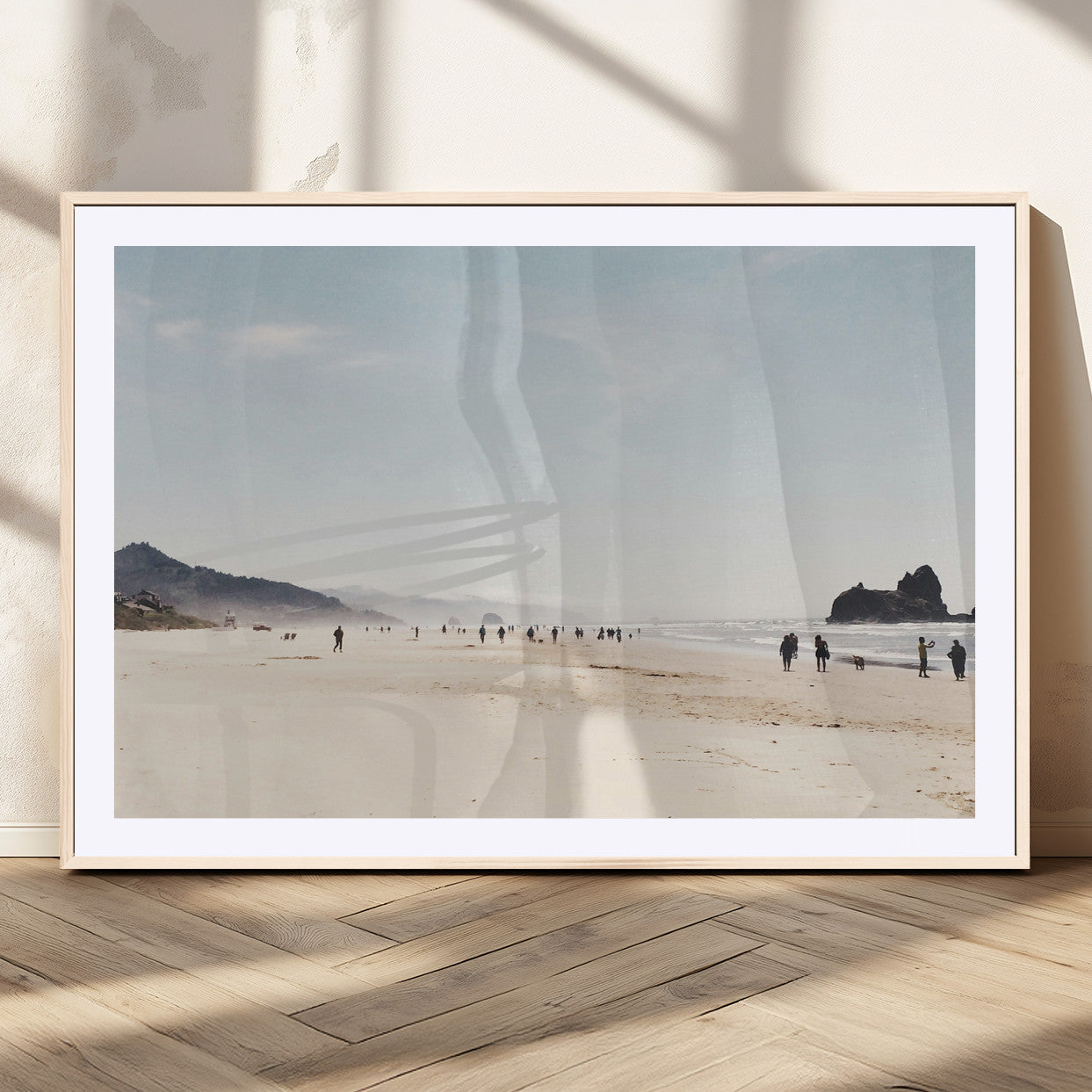 A serene beach with soft sand, misty mountains, and scattered people walking along the shoreline, creating a peaceful coastal landscape.