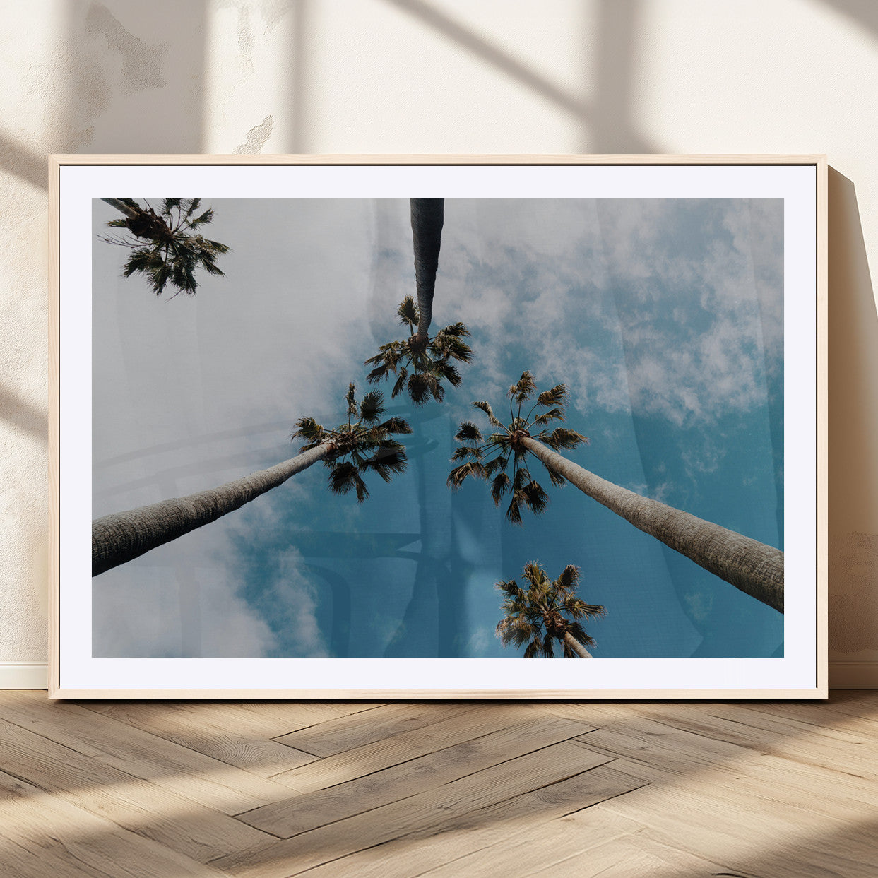 Looking up at tall palm trees against a bright blue sky with scattered clouds, creating a tropical and airy atmosphere for modern home decor.