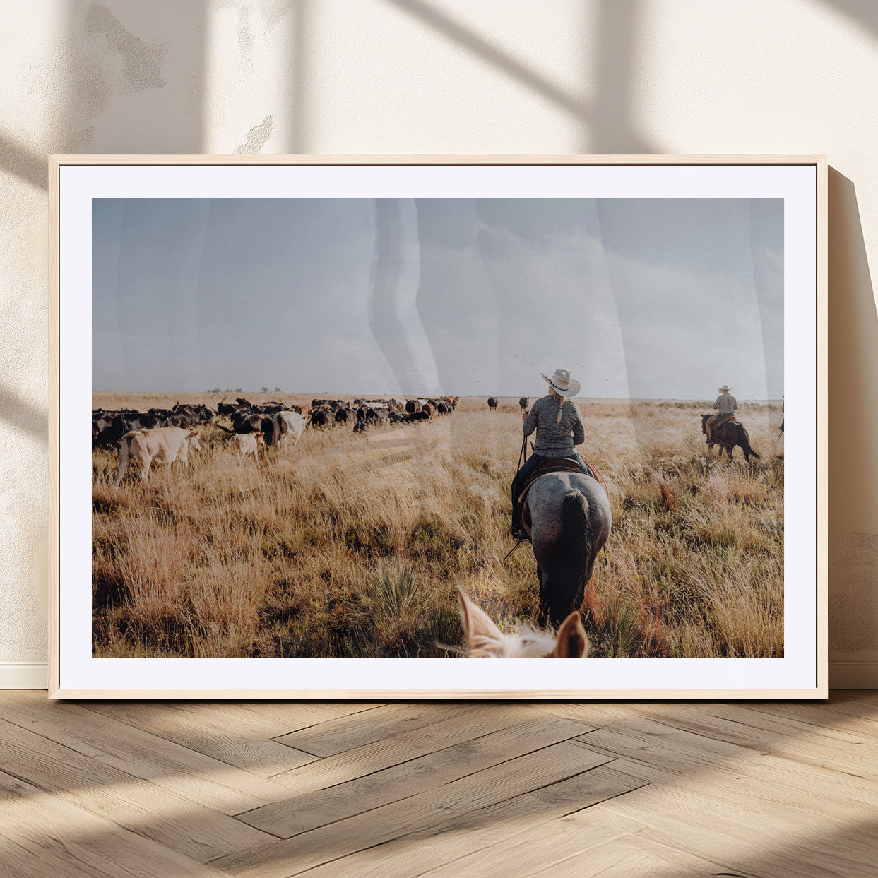 A cowboy and cowgirl on horseback herding cattle through golden grasslands, capturing a rustic and authentic Western ranch lifestyle.
