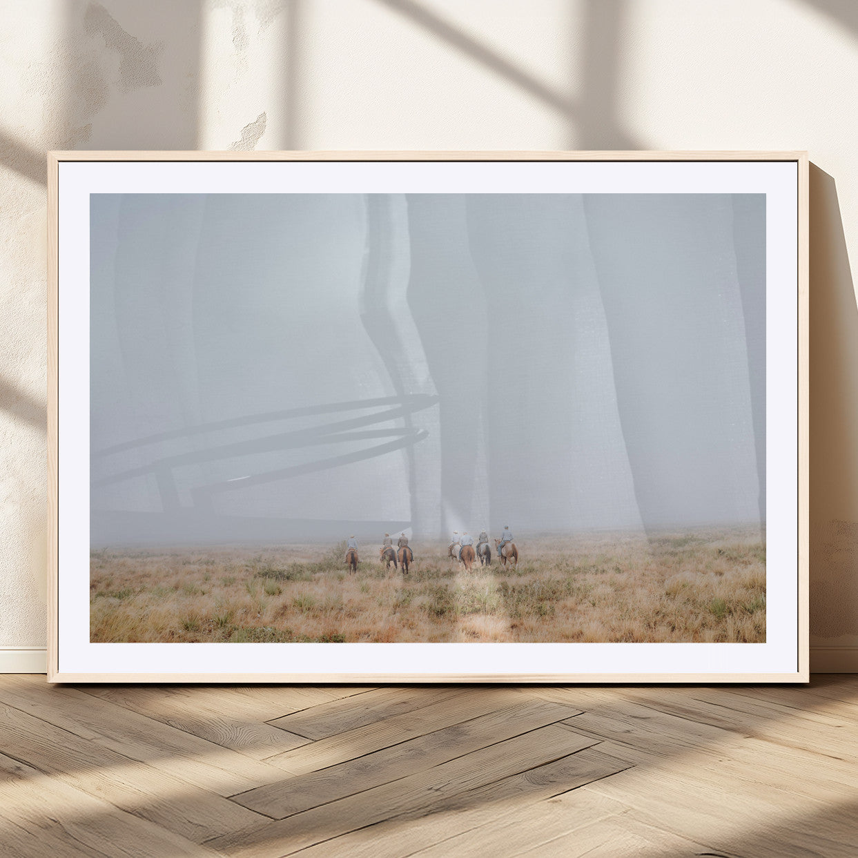 A group of horseback riders moving through a fog-shrouded field, evoking a calm Western scene with golden grasses and soft horizons.