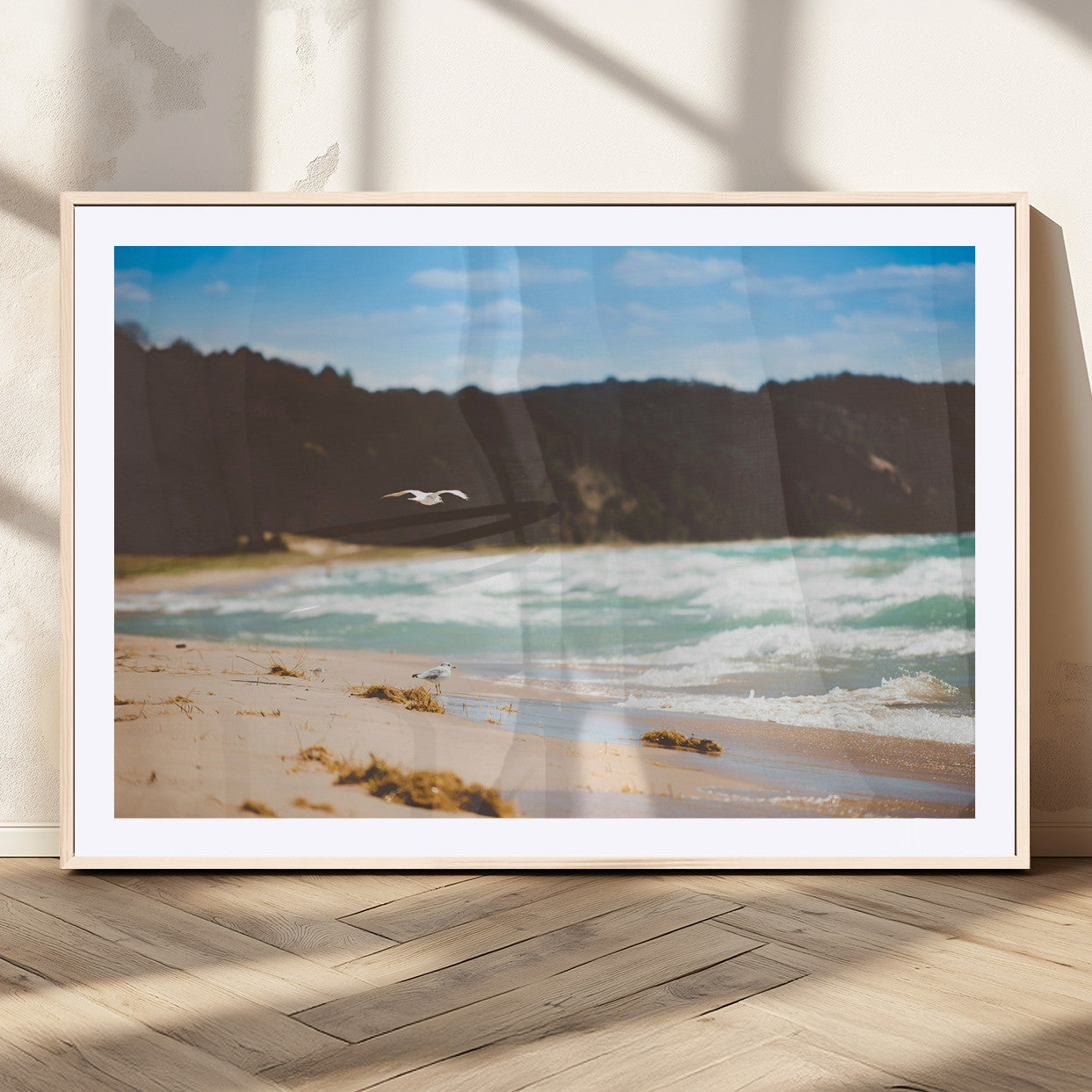Serene beach scene with gentle ocean waves, sandy shore, and a seagull flying under a blue sky, perfect for coastal and nature-inspired decor.