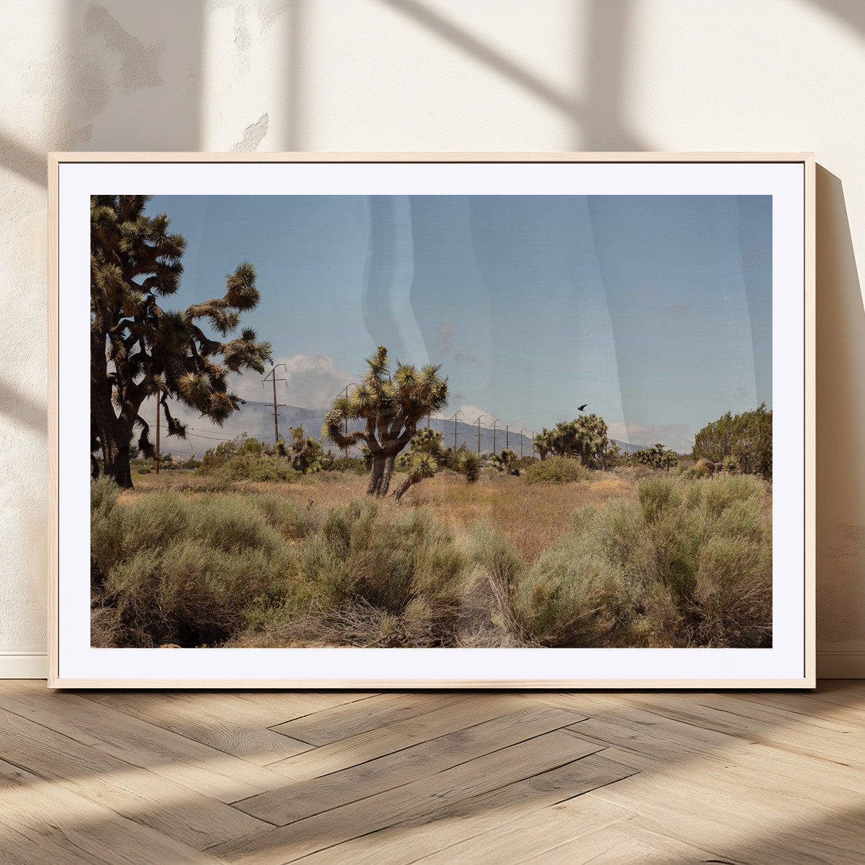 Scenic desert landscape with Joshua trees, dry grass, and distant mountains under a clear blue sky, perfect for southwestern and rustic decor.