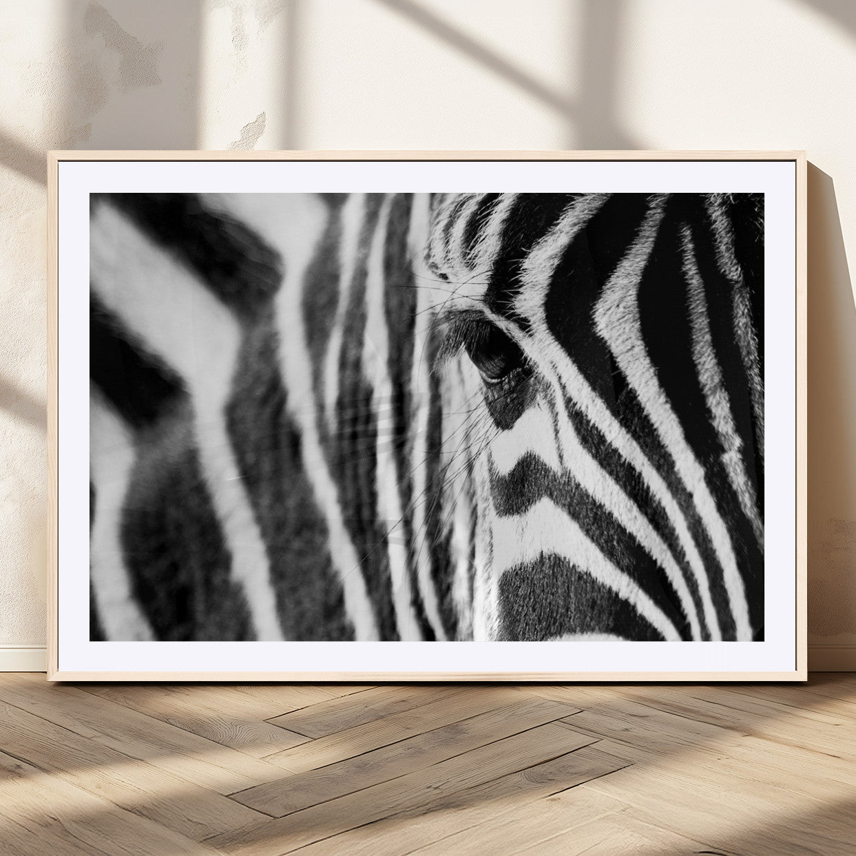 A close-up black and white photograph of a zebra's eye, showcasing the intricate patterns of its stripes in sharp detail.
